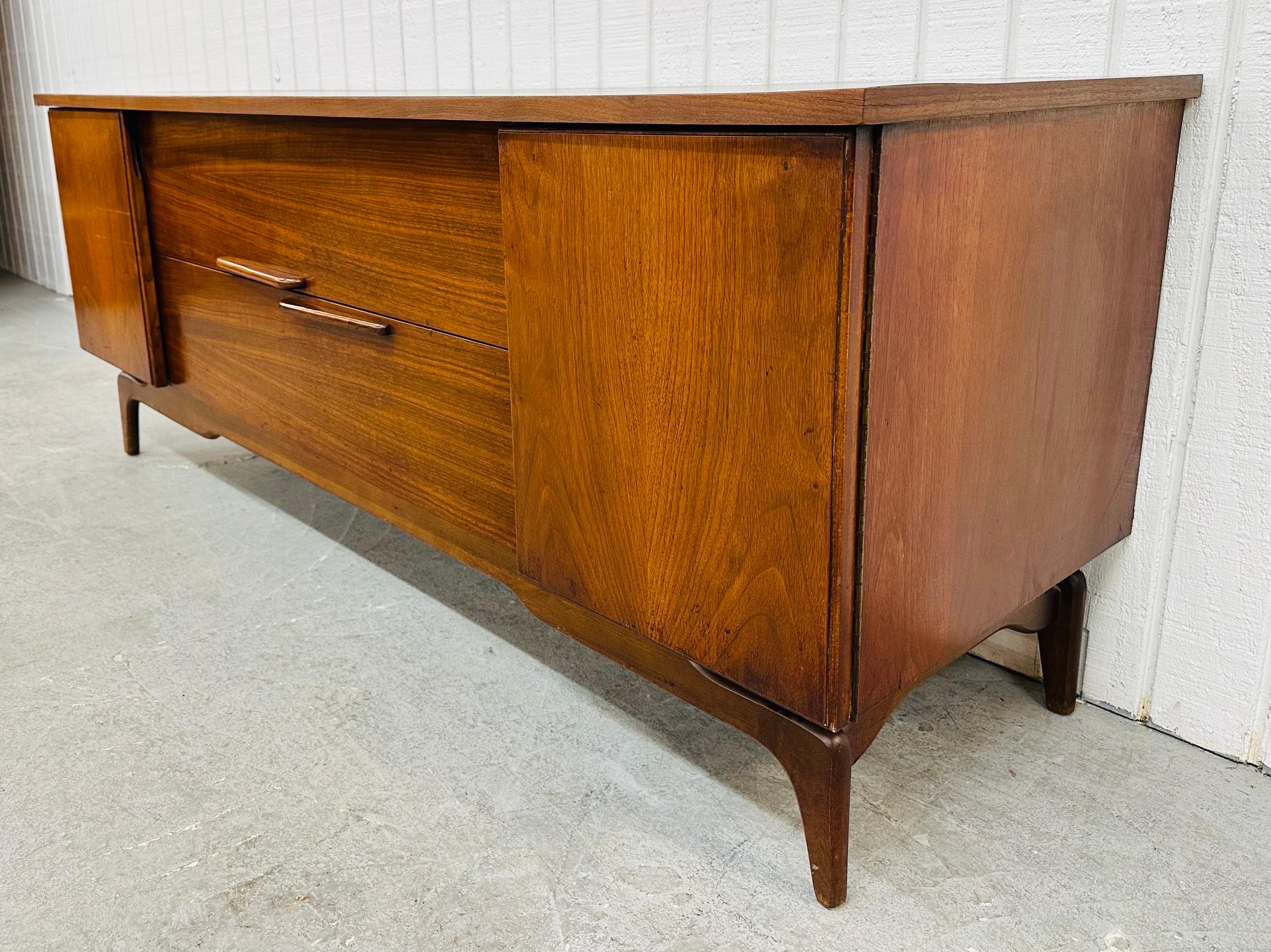 This listing is for a Mid-Century Modern John Cameron Walnut Sideboard. Featuring a straight line design, two doors that open up to storage space, two center drawers with wooden handles, freeform modern legs, and a beautiful walnut finish. This is