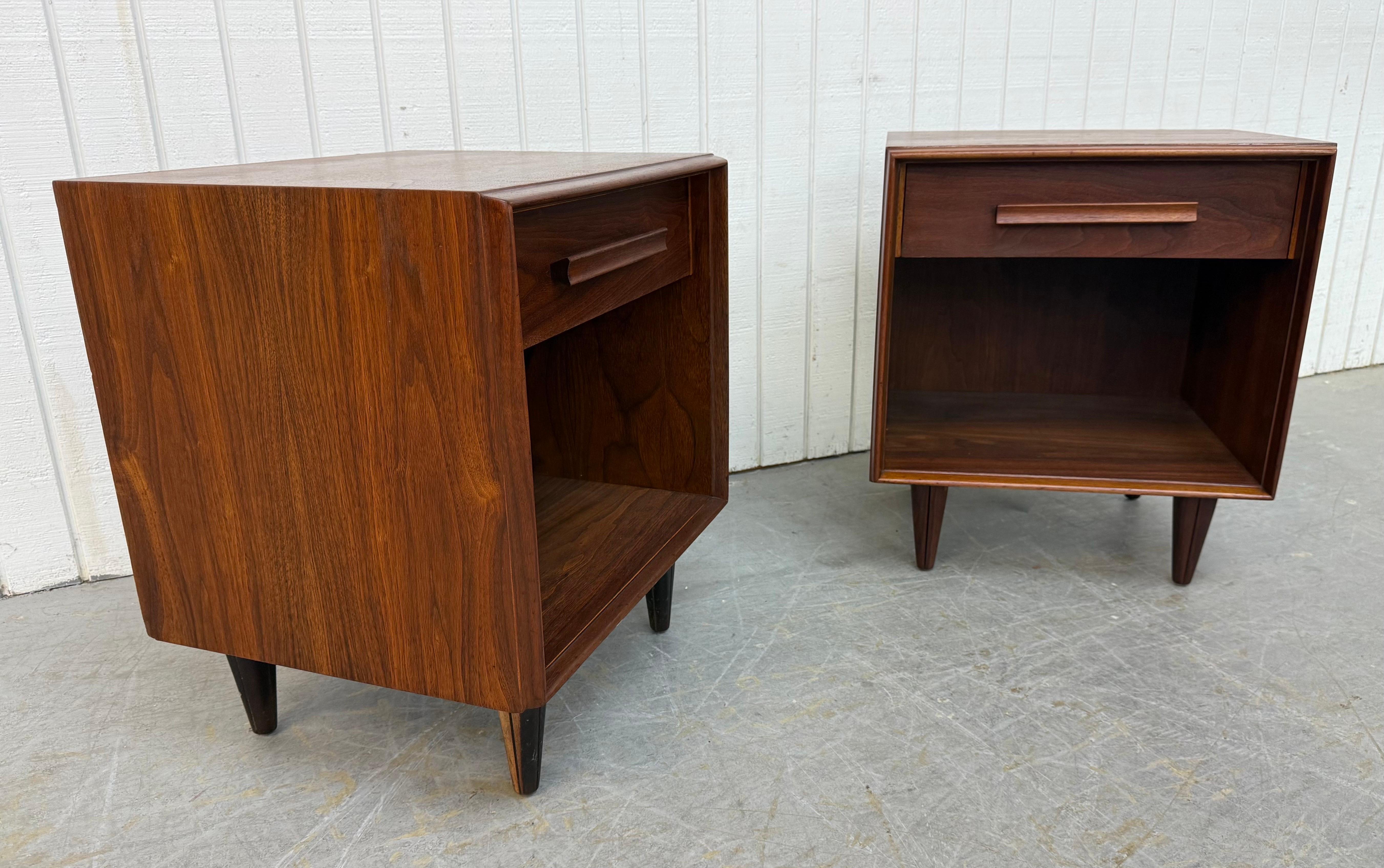 Questo annuncio si riferisce a una coppia di comodini in noce John Widdicomb della metà del secolo scorso. Caratterizzato da un design a cubo dalle linee rette, cassetto singolo con tiretto in legno, spazio aperto per riporre gli oggetti, gambe