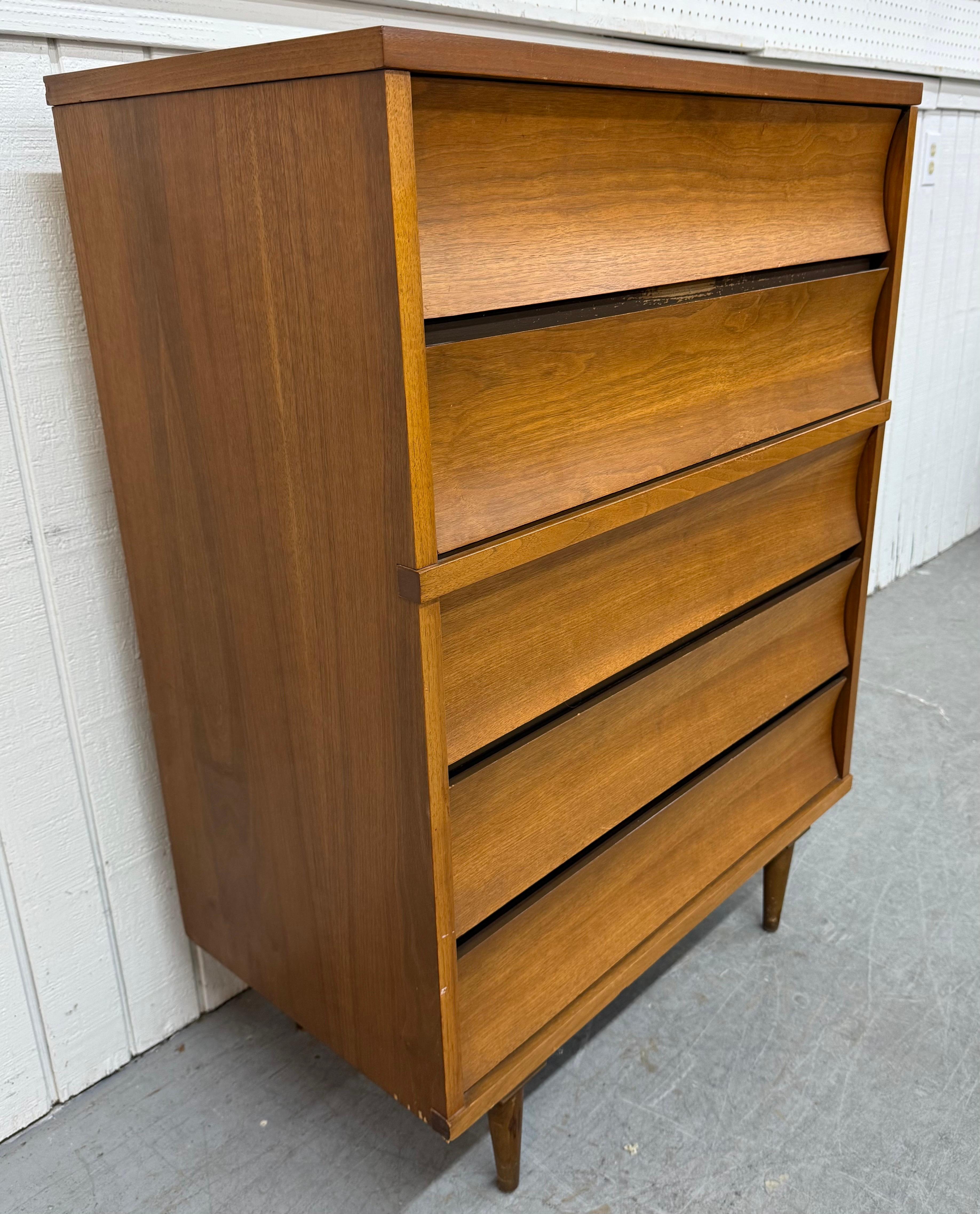 This listing is for a Mid-Century Modern Johnson Carper Walnut Concave High Chest. Featuring a straight line design, five concave style drawers, a protective laminated top, modern legs, and a beautiful walnut finish. This is an exceptional