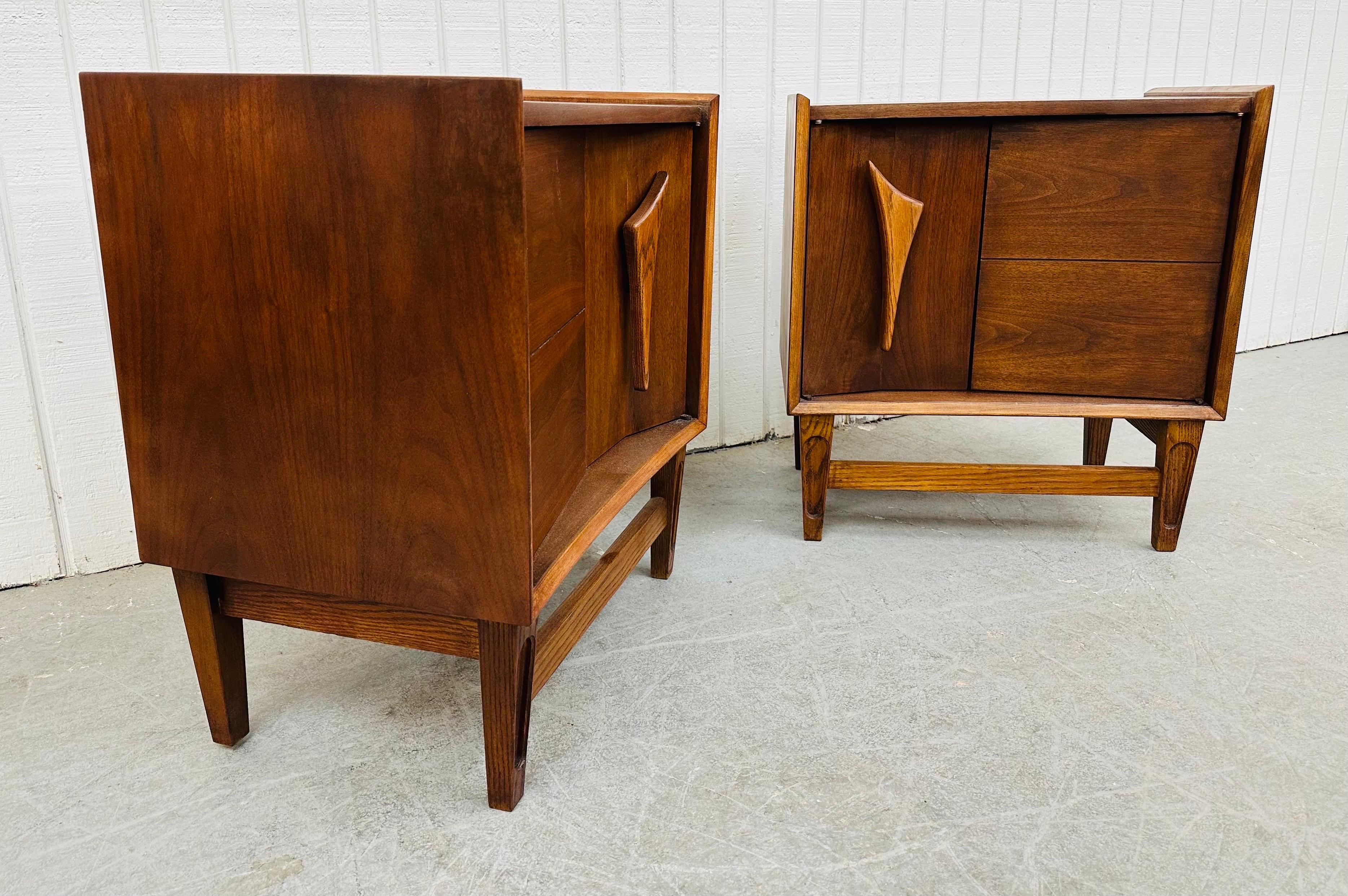 This listing is for a pair of Mid-Century Modern Kagan Style Walnut Nightstands. Featuring a straight line design, two doors that open up to storage space, modern legs with stretcher base, and sculpted wooden pulls. This is an exceptional