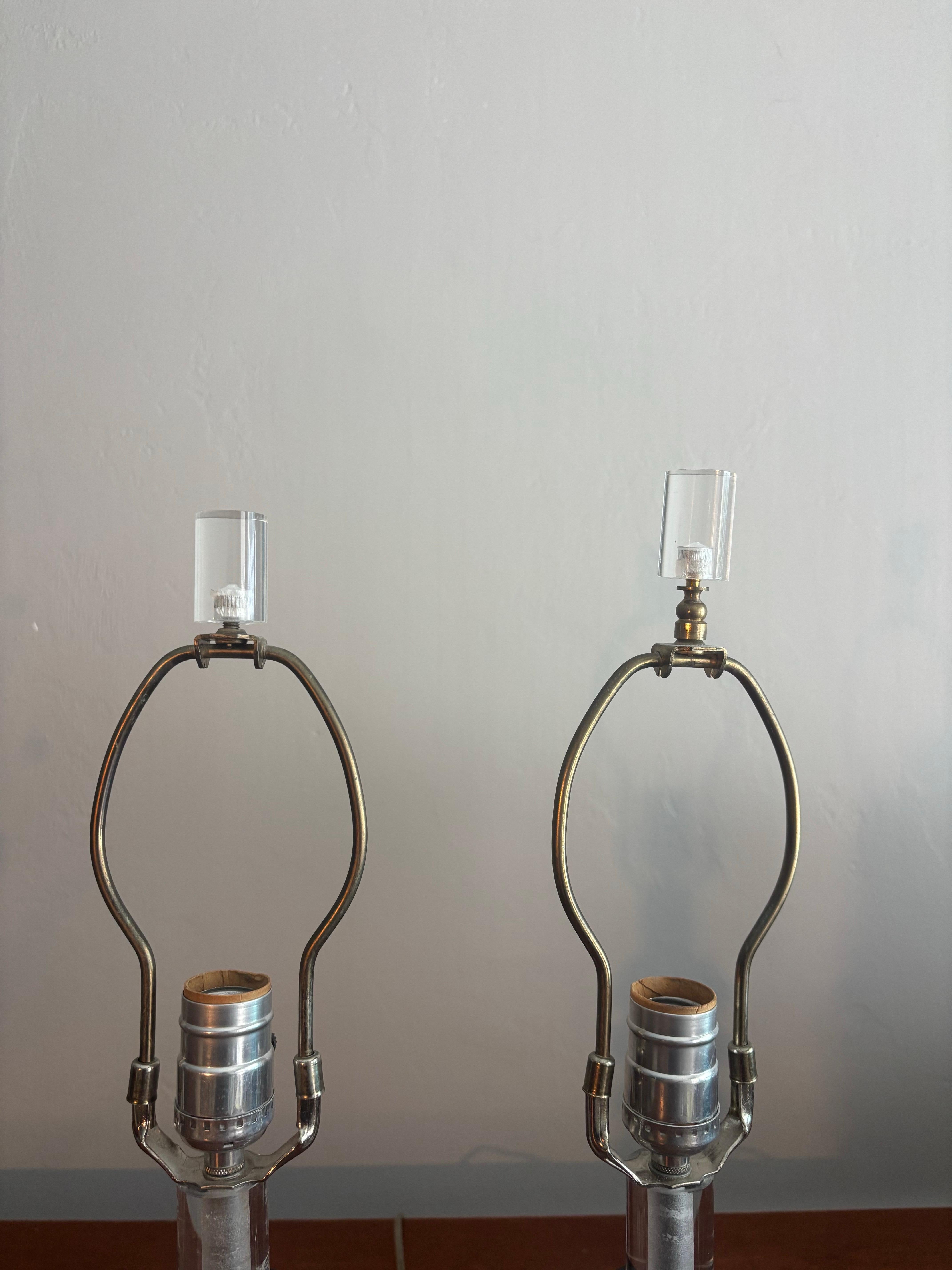 Beautiful pair of stacked lucite table lamps. 

In the manner of Karl Springer. 

Lucite bulbs stacked separated by black lucite disks. Exceptionally fun design. They look classy while bringing a taste of whimsy. 

Lamps are 21