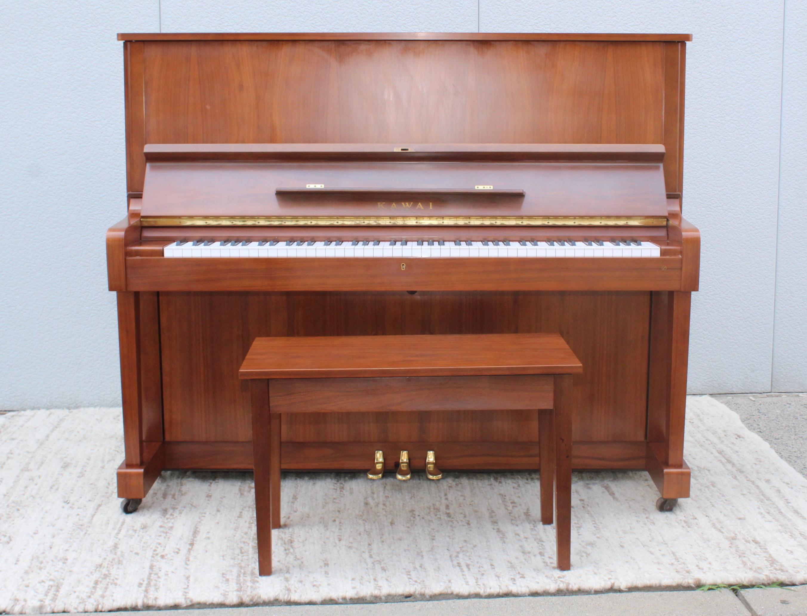 Stunning 1960s modern Kawai upright piano made of walnut with brass hardware model number K1490204. With the original stool and two keys.