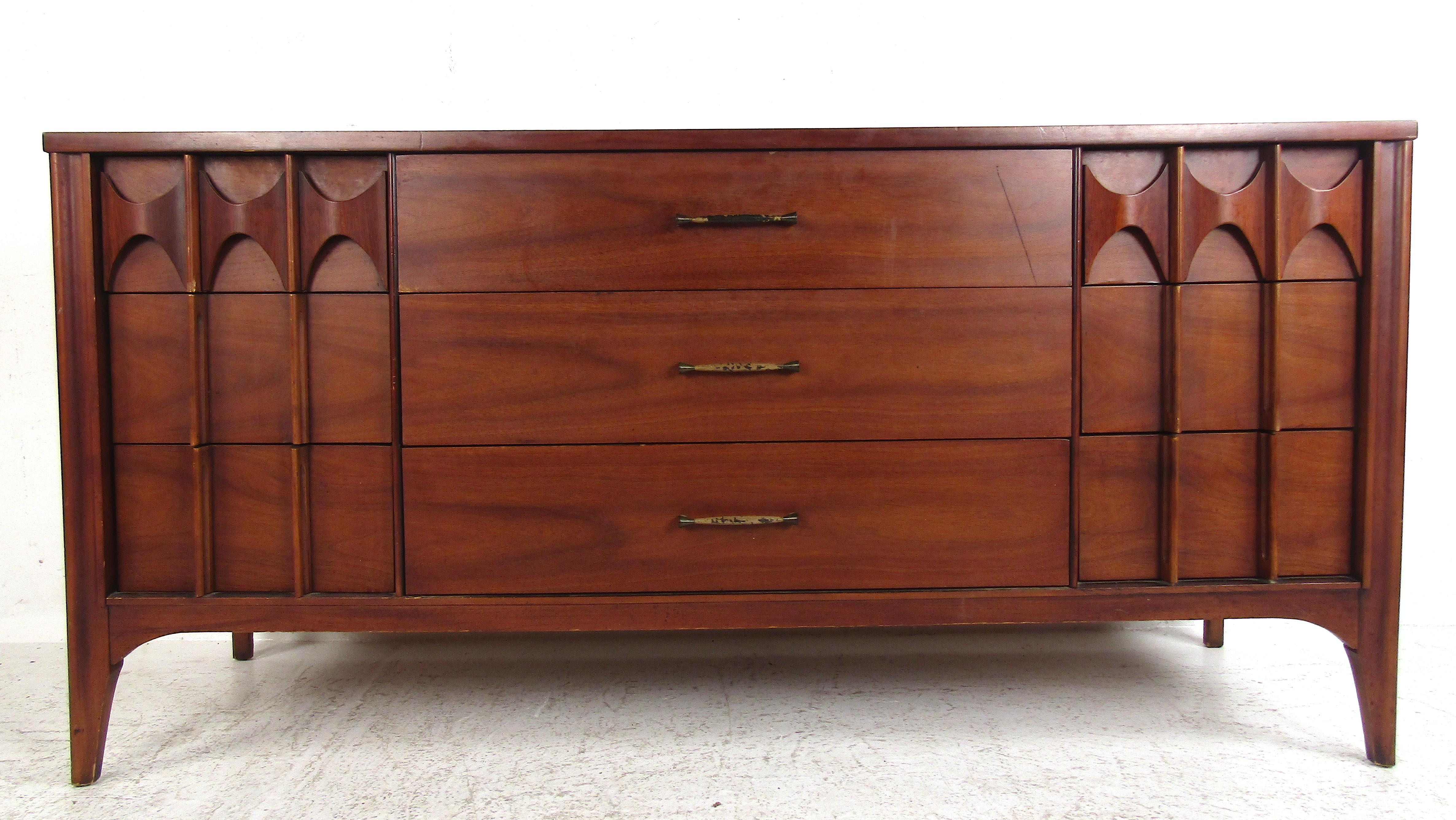 This beautiful vintage modern dresser features sculpted rosewood handles and a walnut casing. A spacious nine drawer dresser that provides ample storage space without sacrificing style. Elegant walnut wood grain makes this a beautiful addition to