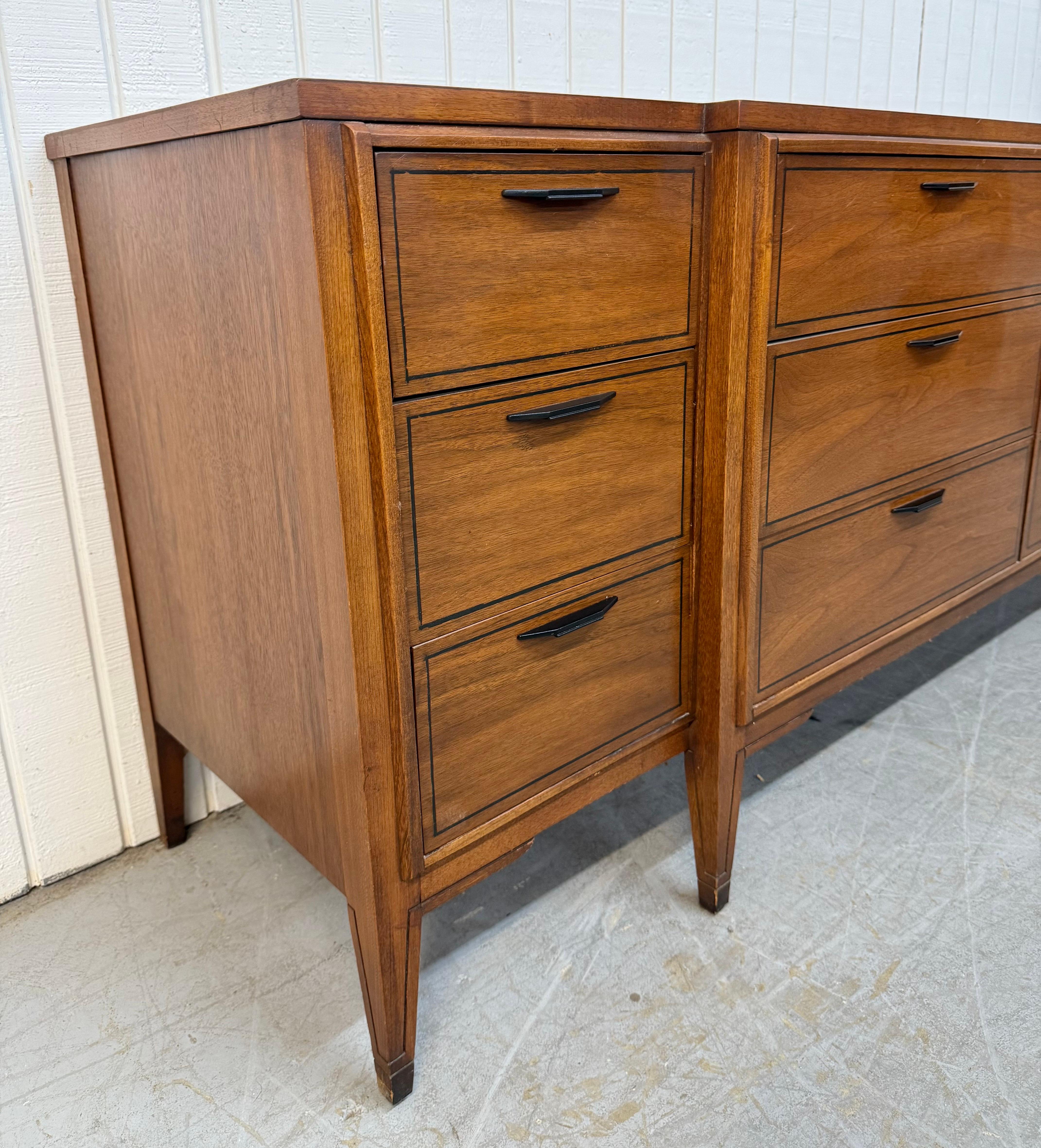 Questo annuncio si riferisce a un comò in noce a 12 cassetti di Kent Coffey, in stile Mid-Century Modern. Il design è lineare, i cassetti sono dodici, le gambe sono moderne, la ferramenta è nera e la finitura è in noce. Questa è un'eccezionale