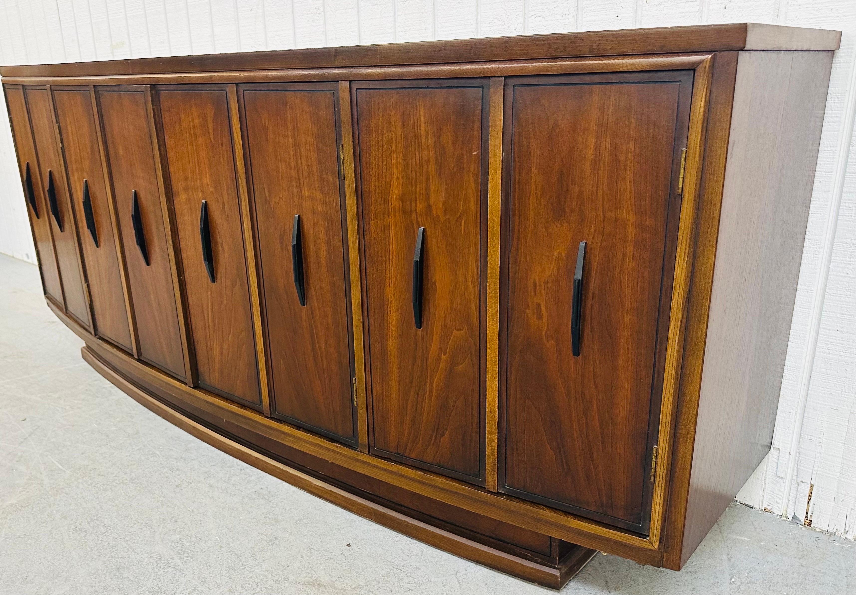 This listing is for a Mid-Century Modern Kent Coffey Walnut Credenza. Featuring a curved front design, two doors on each end that open up to storage space, two doors in the center that reveal three hidden drawers, original black hardware, and a