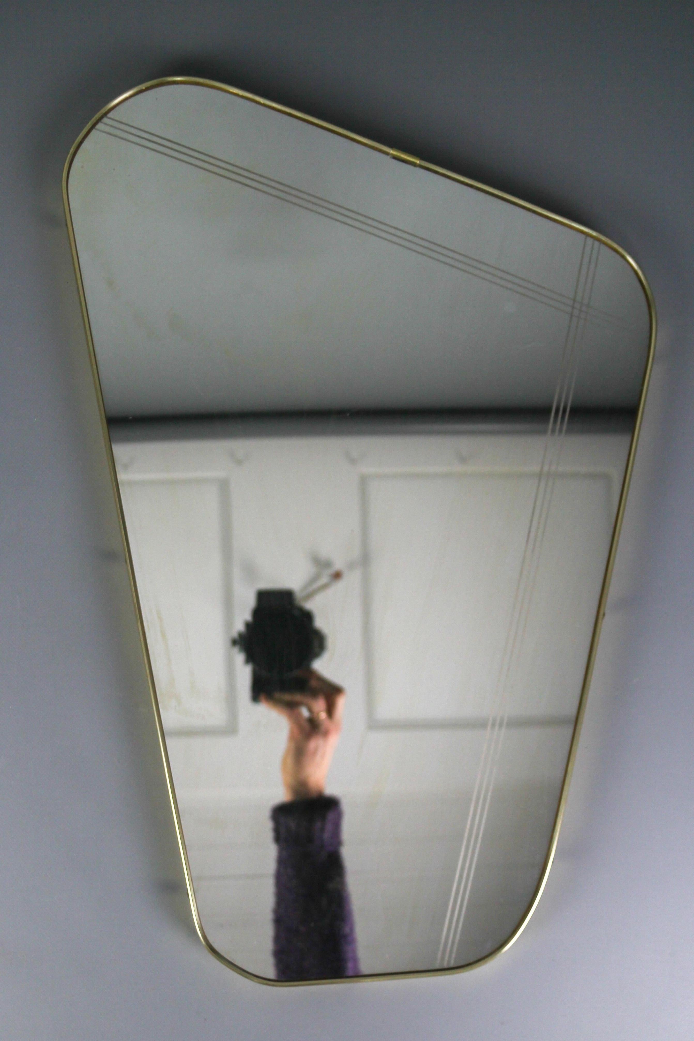Vintage Mid-Century Modern nierenförmiger asymmetrischer Wandspiegel mit einem schönen goldfarbenen Kunststoffrahmen und Messingknöpfen, Rückwand aus Furnier. Deutschland, um die 1960er Jahre.
Abmessungen: Höhe: 57 cm / 22.44 in; Breite: 38,5 cm /