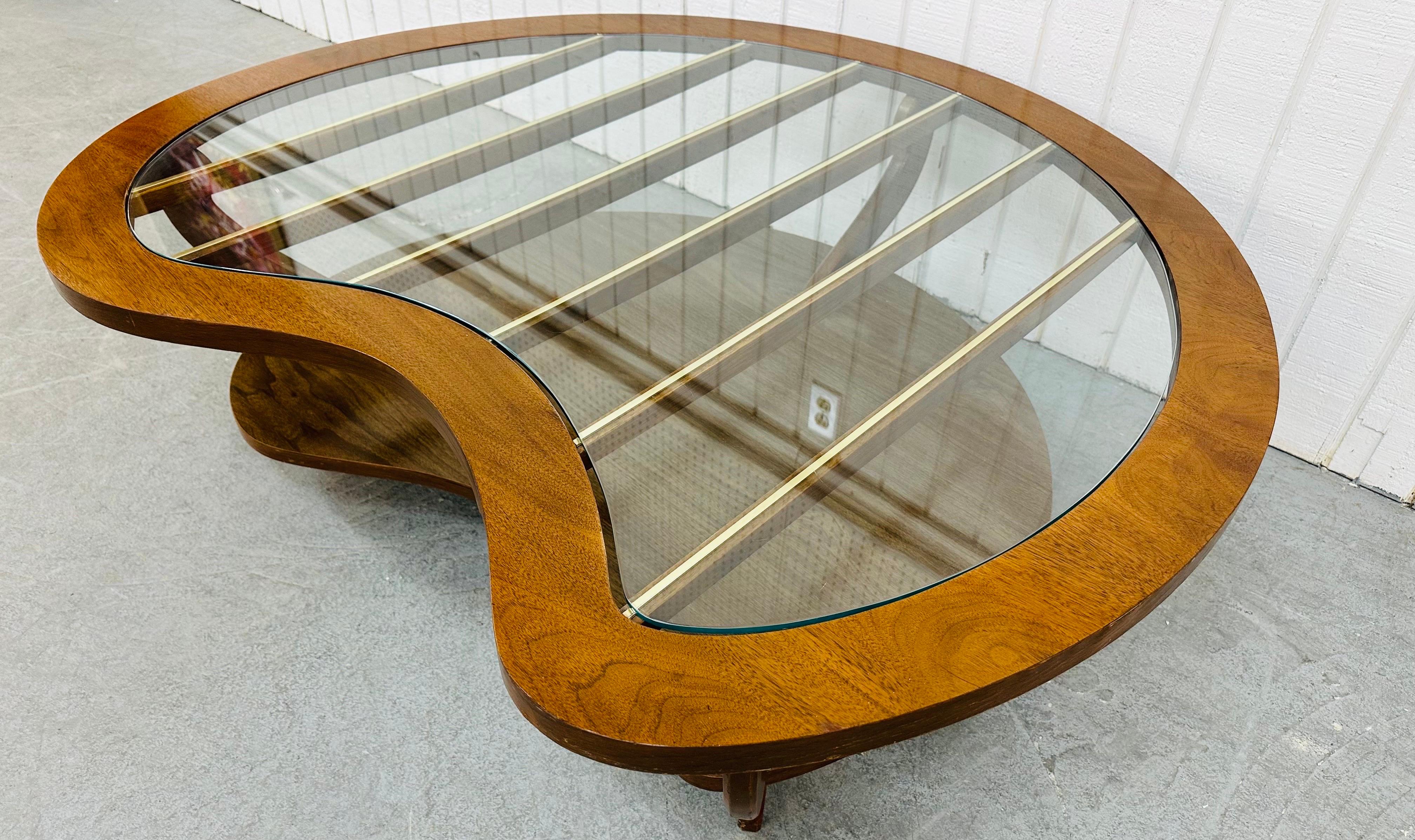 This listing is for a Mid-Century Modern Kidney Shapes Walnut Coffee Table. Featuring a kidney shaped top, glass insert, brass accented rails under the glass, a bottom tier for storage, modern legs, and a beautiful walnut finish. This is an