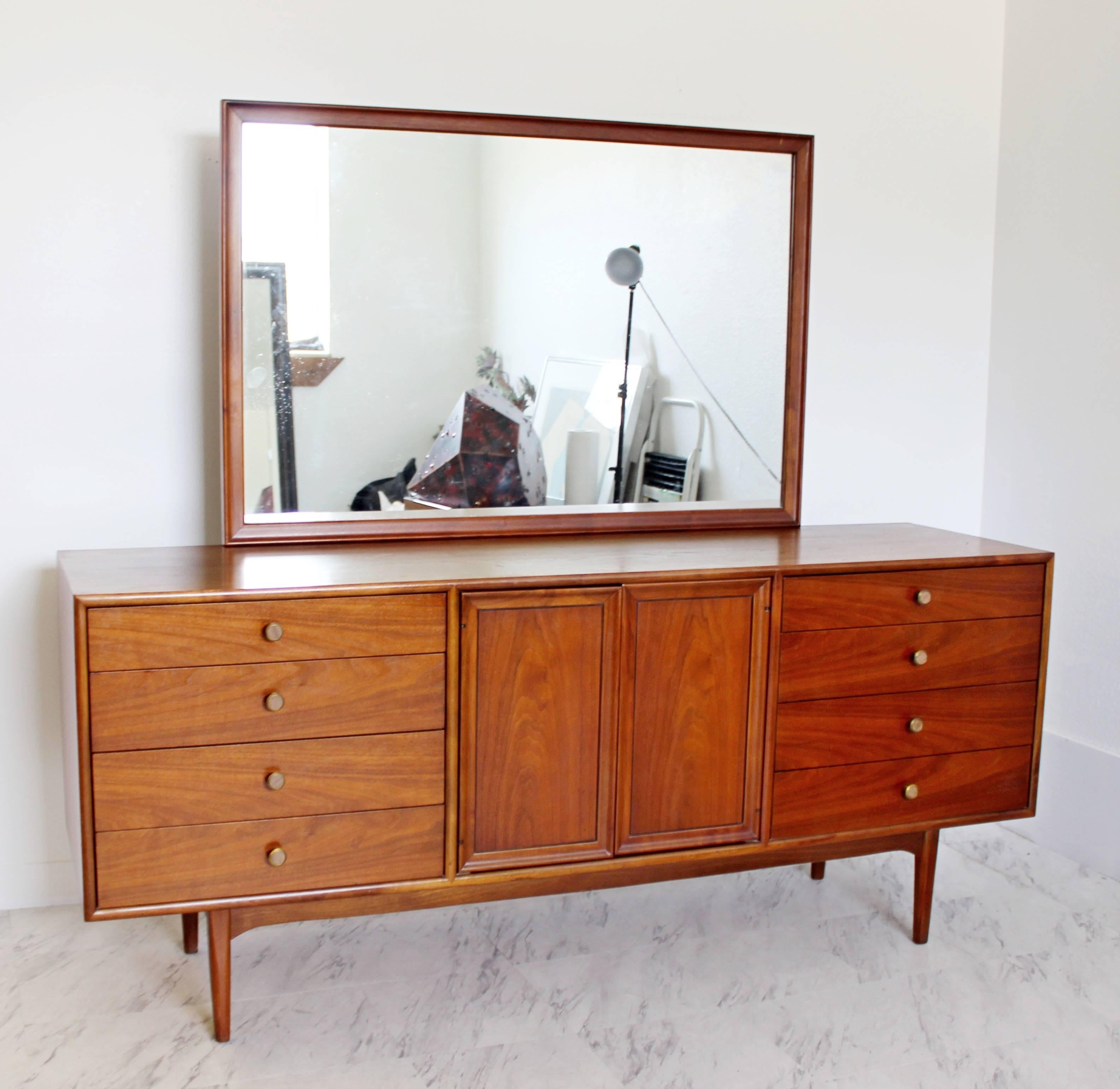 For your consideration is a stunning, walnut lowboy, with an attached mirror and brass and wood knobs on its eight outer drawers, designed by Kipp Stewart for Drexel, Declaration, circa 1965. In excellent condition. The dimensions are 72