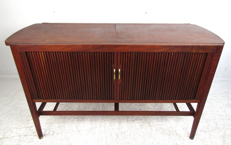 This beautiful vintage modern server features an expanding top that goes from 49.5 inches all the way to 84 inches. Two walnut leaves slide in opposite directions unveiling a black laminate top. A sleek design with tambour doors that hide a large