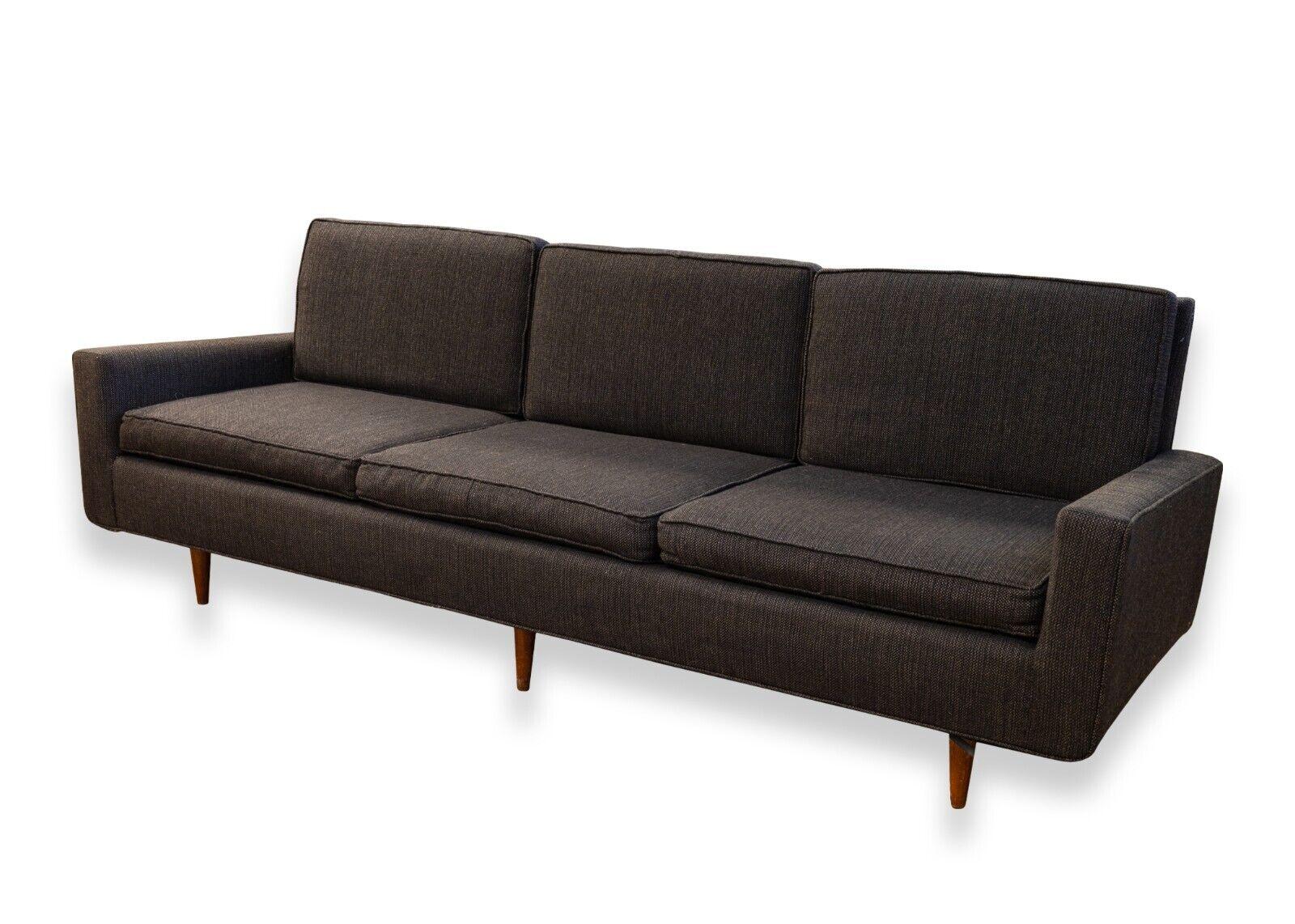 A mid century modern Knoll 1950's black sofa with wooden legs. A wonderful black sofa from Knoll featuring a classic, timeless design. This piece features a black upholstery from head to toe, six beautiful wooden legs, and removable cushions. This