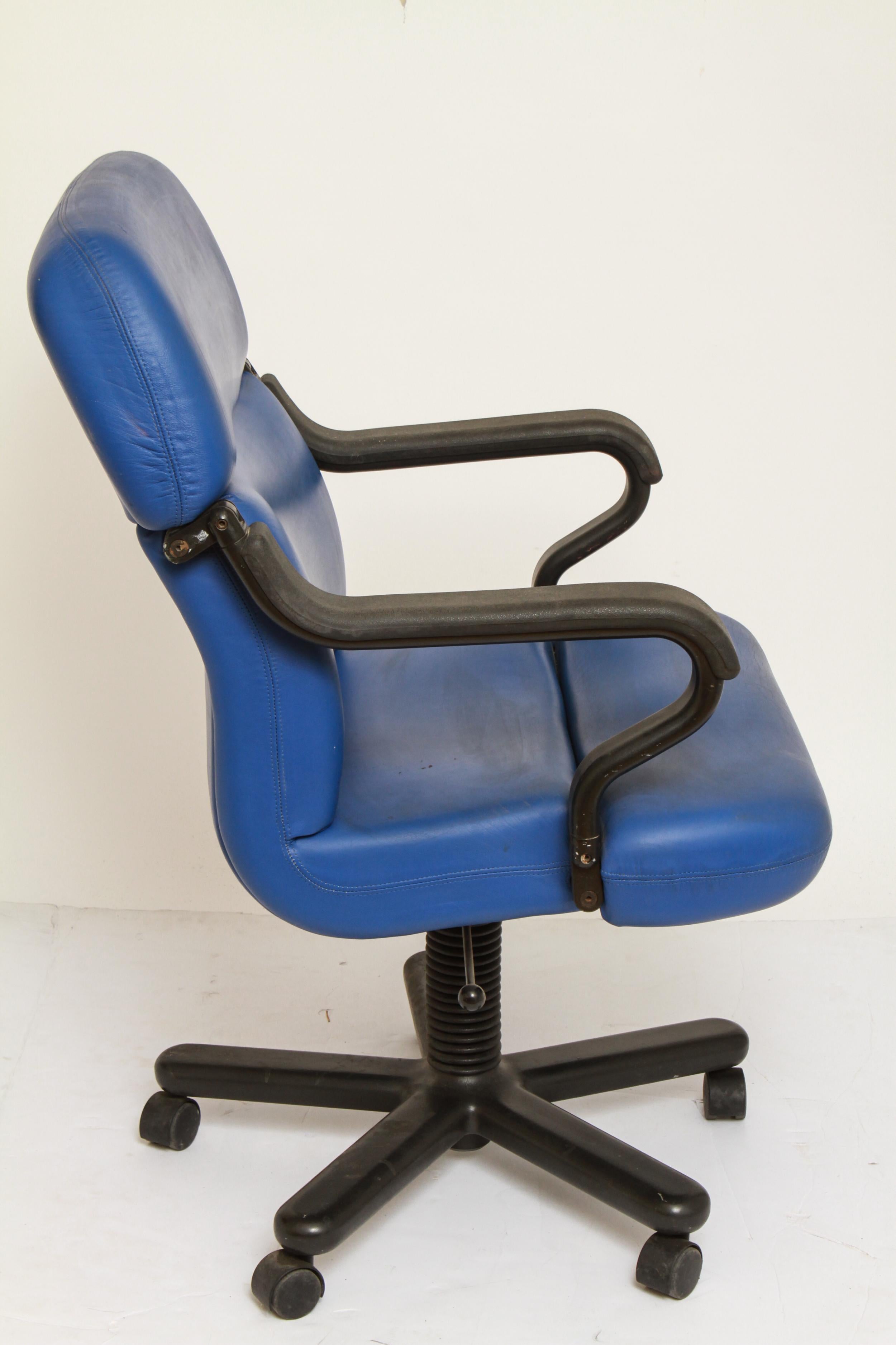 Mid-Century Modern executive office chair in the style of Knoll with blue leather-upholstering and with a molded black plastic frame, on five wheeled legs. The piece is in great vintage condition. From the estate of Peter Knoll.