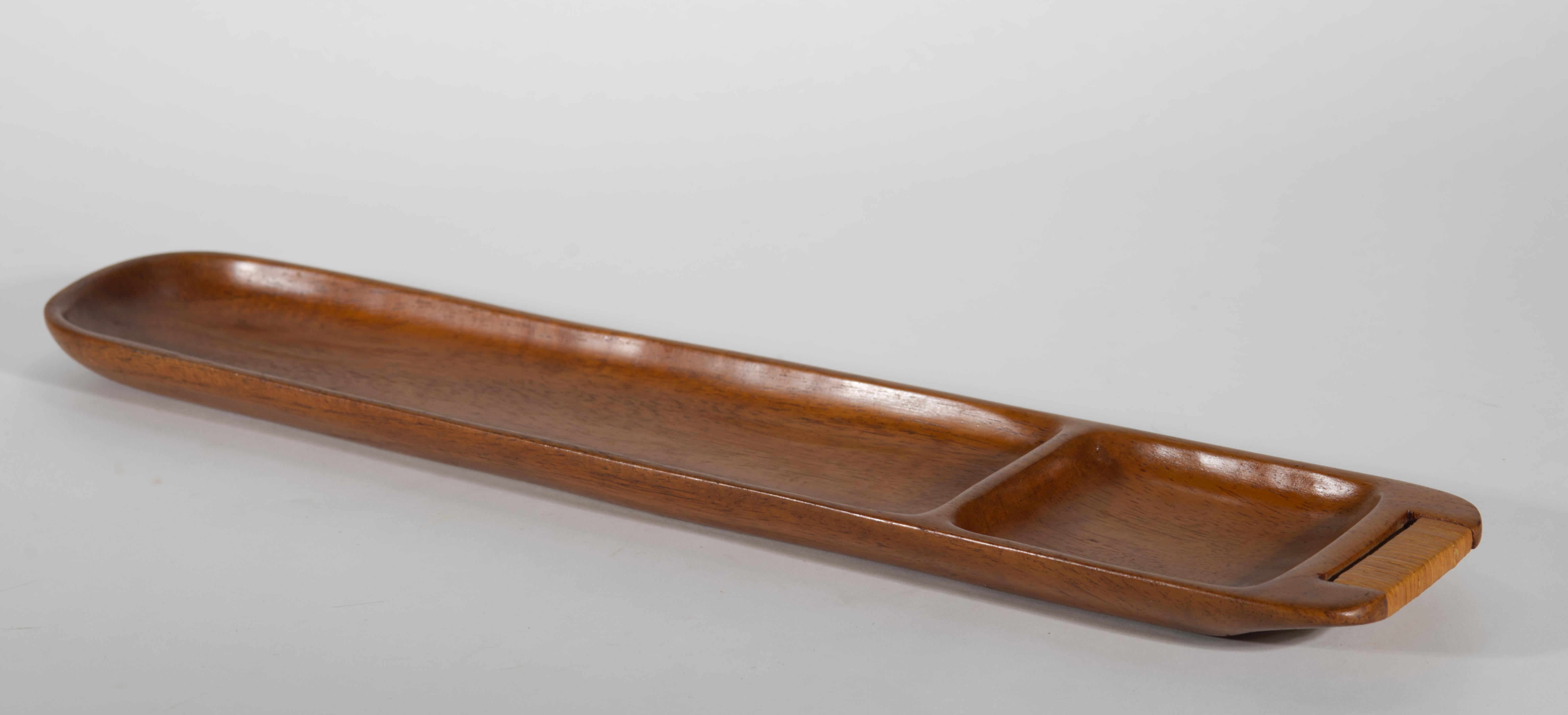 Le plateau rectangulaire en bois vintage sculpté à la main présente une forme moderniste et des motifs graphiques de grain de bois avec une gamme de tons naturels. La poignée est enveloppée de roseau ou de canne. La forme minimale du plateau met en