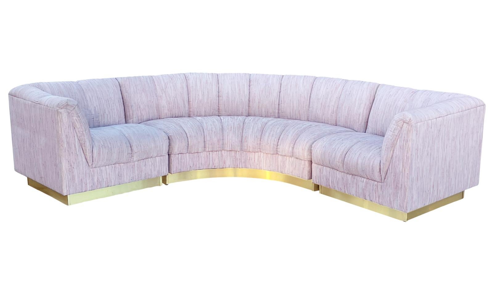 A post modern curved sectional circa 1980's. It features a 3 piece design with brass plinth base. Fabric is original and needs updating. Overall depth is 34 inches.