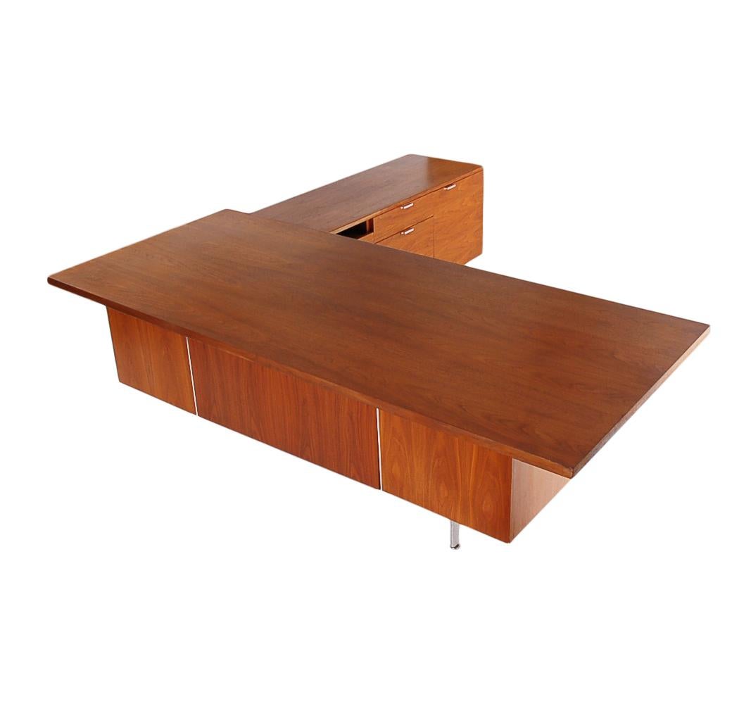 A large and impressive executives desk with return. This desk is from the 1960s, designed by George Nelson, and produced by Herman Miller. It features beautiful walnut construction, with stainless steel accents. In very well cared for condition.