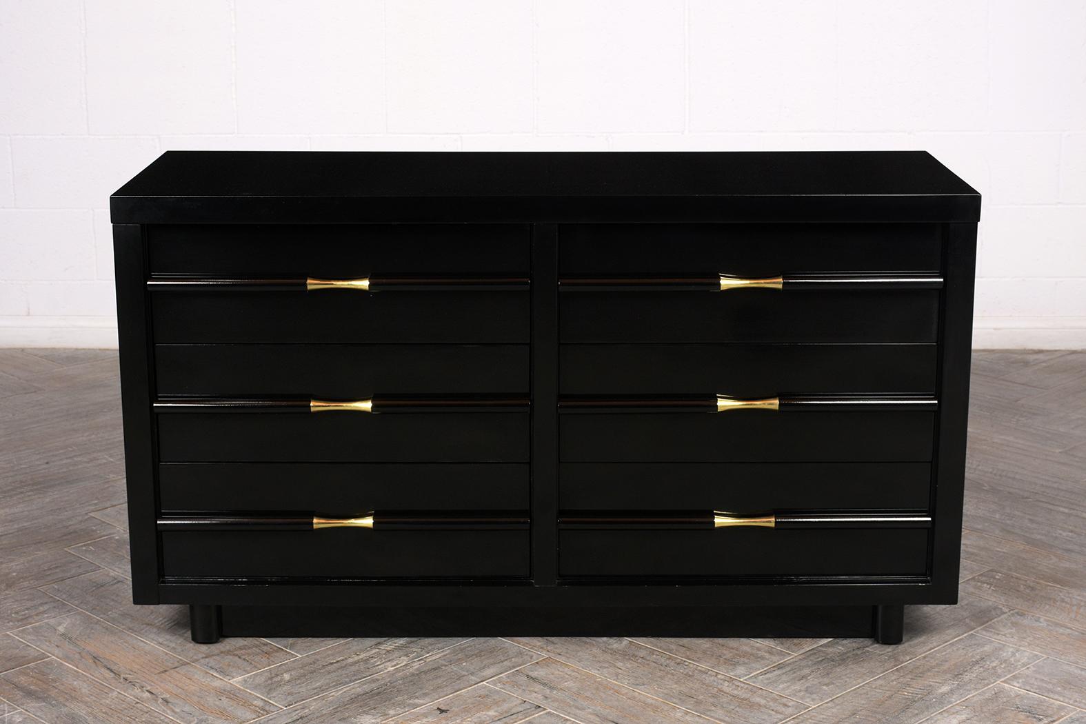 This Mid-Century Modern maple wood chest of drawers has been completed restored have a newly black lacquered finish. It has six drawers a large carved wood handles with unique brass detail, this piece resting on a floating base. All the drawers are
