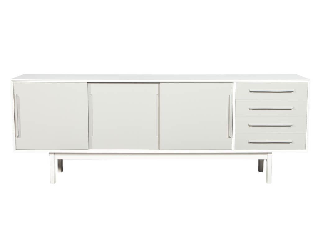 Mid-Century Modern lacquered sideboard media cabinet. Finished in a two-tone designer white and dove grey satin lacquer. This sideboard has clean modern lines and sliding doors and drawers for convenient storage. Restored by the artisans here at
