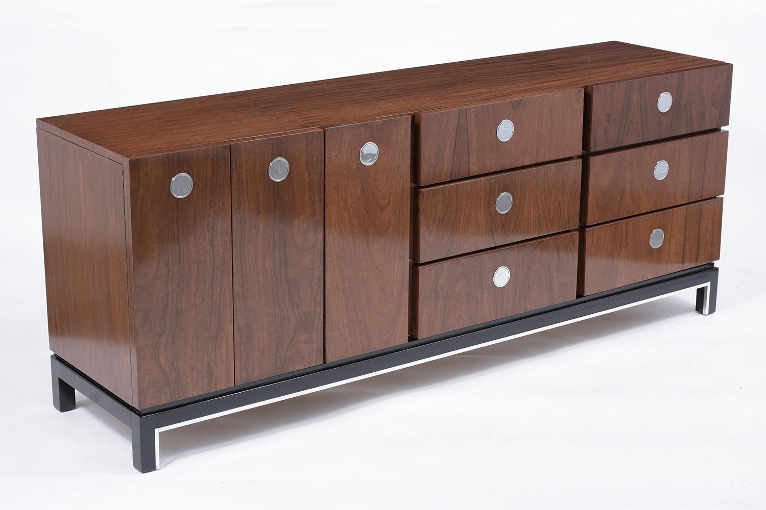 An elegant Mid-Century Modern walnut dresser has been professionally restored, is crafted out of walnut wood, and is newly stained in walnut and ebonized color combination with a lacquer finish. This credenza features six drawers on the left side