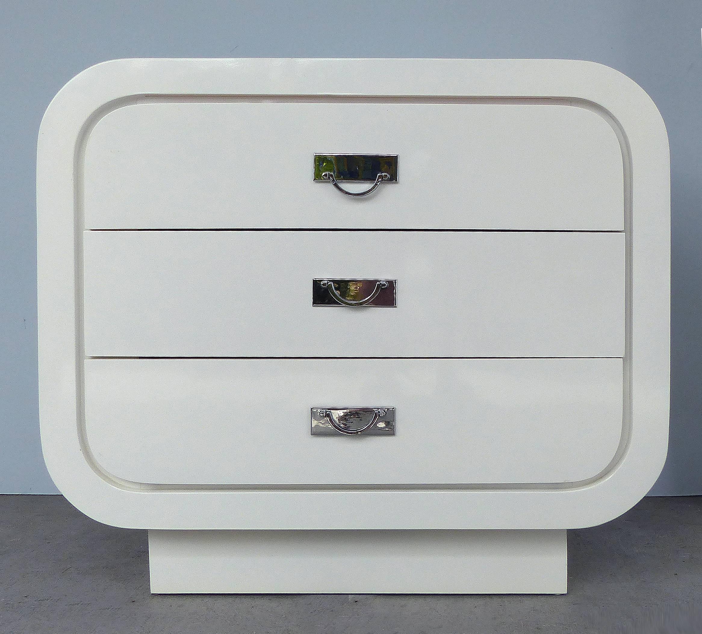Offered for sale is a pair of Mid-Century Modern white lacquered chests with rounded edges, three drawers and chrome-plated hardware. The chests are the perfect size to use as night stands.