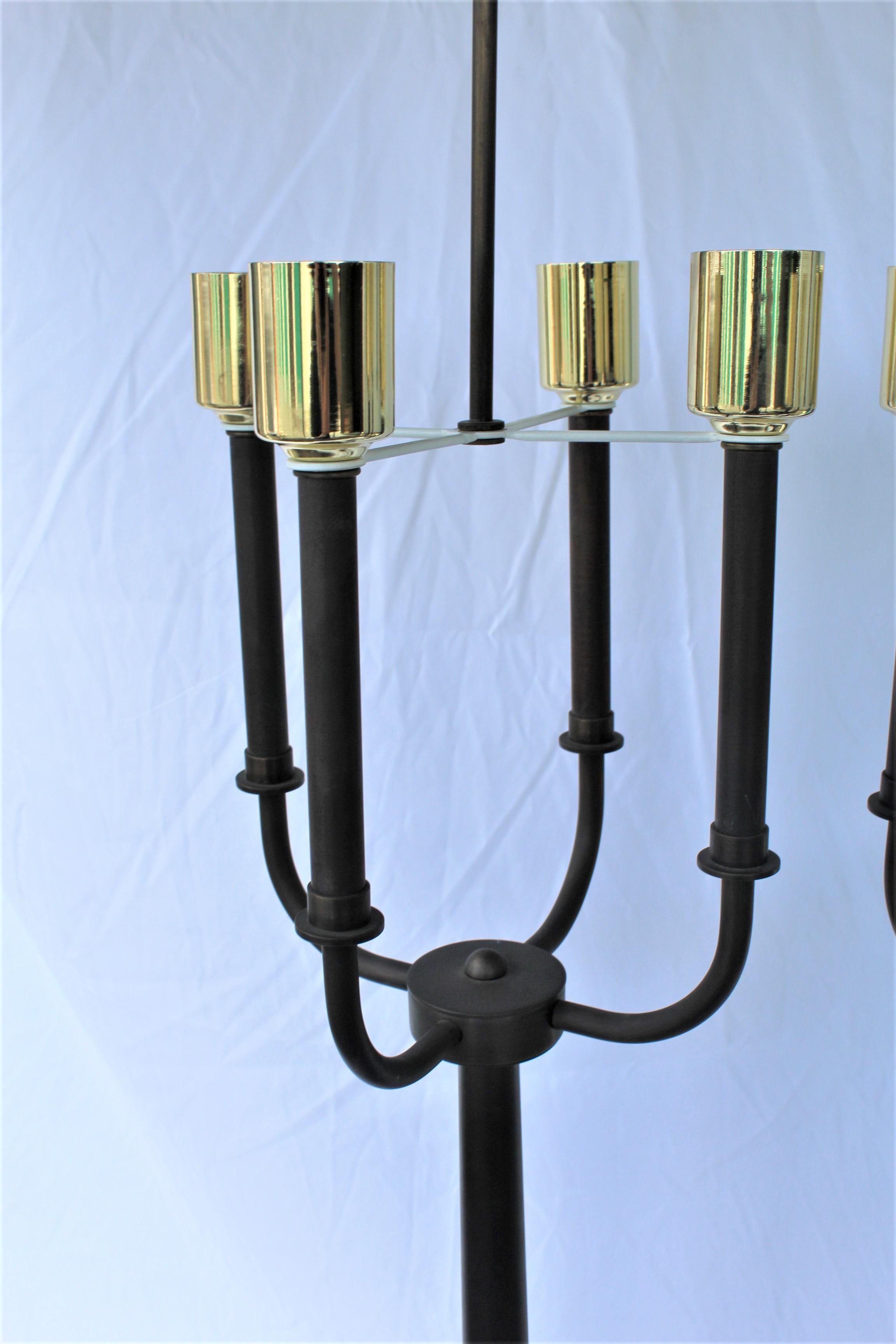 A large pair of solid brass lamps with an antique brass patina finish in the manner of Tommy Parzinger. With a four light cluster body with Edison sockets. Custom made. Tall at 39