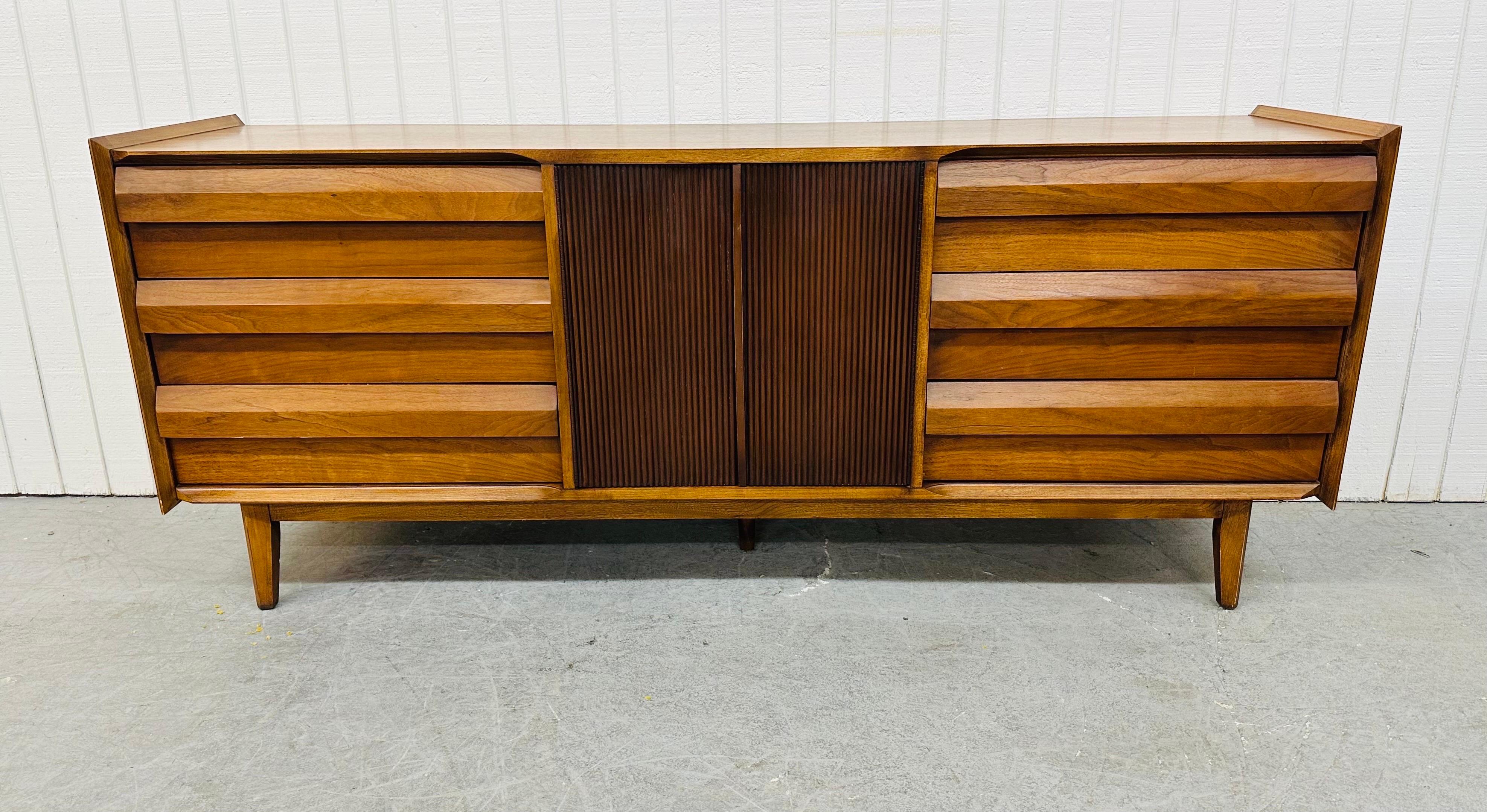 This listing is for a Mid-Century Modern Lane “1st Edition” Walnut Triple Dresser. Featuring a straight line design, three large drawers with louvre style pulls on the left and right side, center doors that open up to three hidden drawers, modern