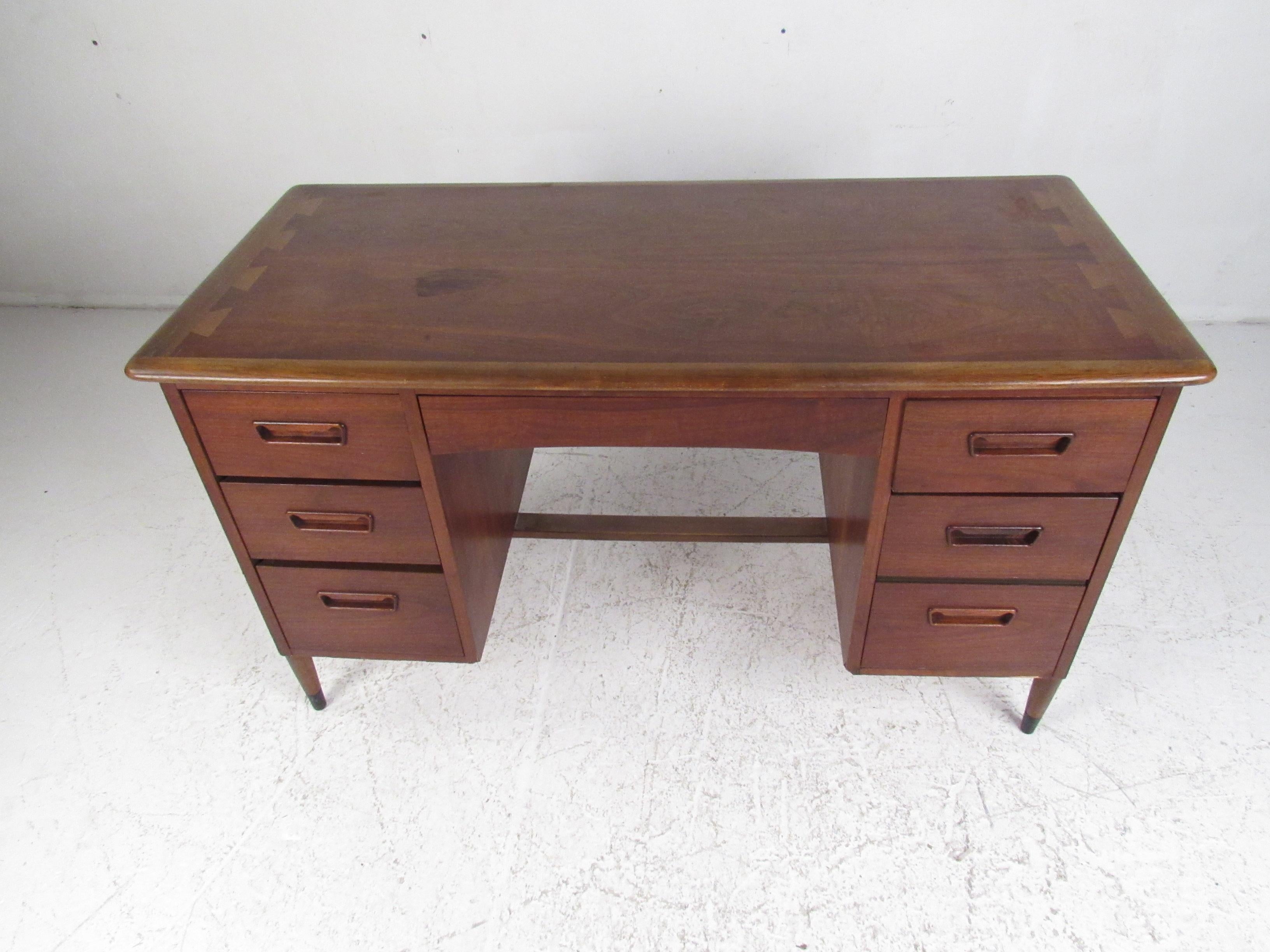 A stunning vintage modern double pedestal desk with six hefty drawers. This stylish two-tone case piece boasts a walnut casing with dovetailed oak inlays around the top. A sleek design with elegant walnut wood grain throughout and tapered legs with