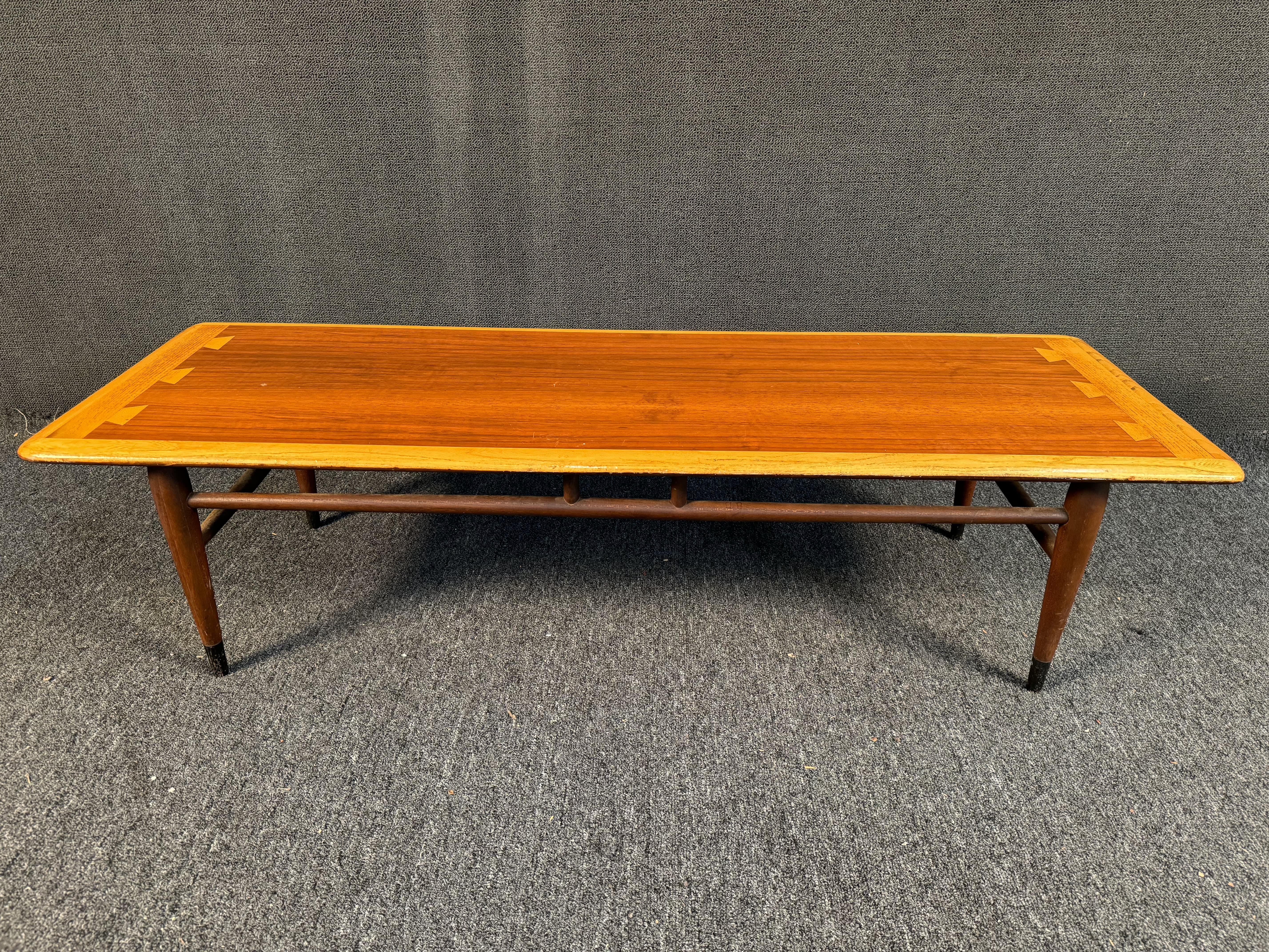 This Mid-Century Modern coffee table in walnut veneered plywood and solid oak was made in Altavista, VA by Lane furniture manufacturer. It has the contrasting dovetail detail on the top that identifies it as part of the Acclaim series from the early