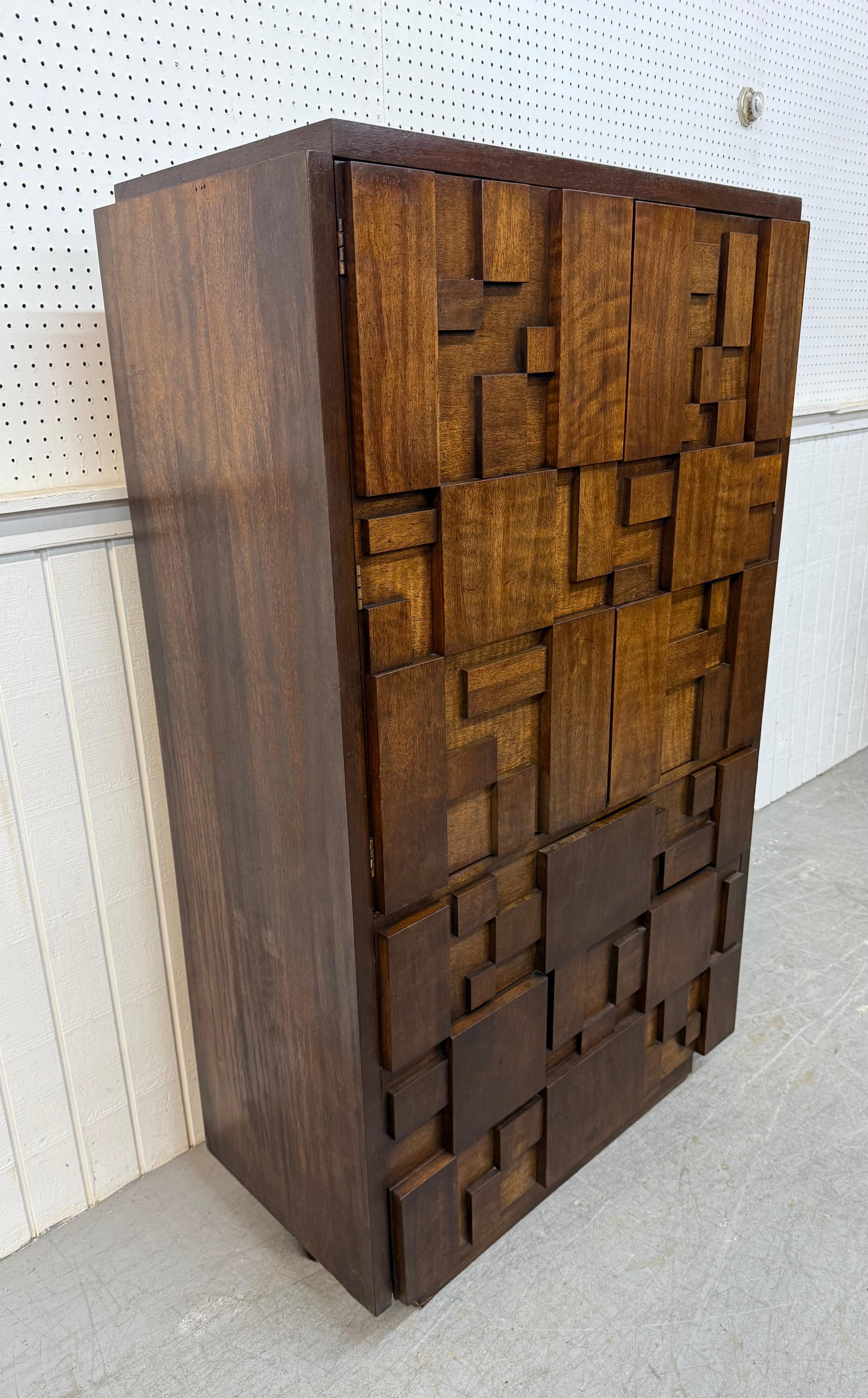 This listing is for a Mid-Century Modern Lane Brutalist Walnut Armoire. Featuring a straight line brutalist block front design, two doors that open up to storage space, small hidden drawer, three larger drawers at the bottom, plinth base, and a dark