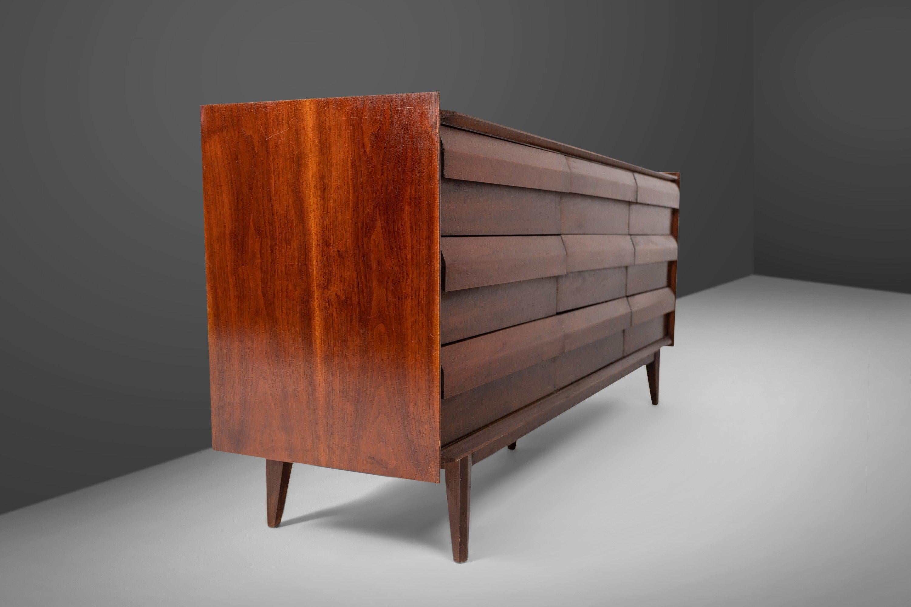 Arguably Lane's most coveted line. The First Addition Line is know for it's cascading angular design. This nine drawer dresser with ample storage is constructed from walnut. Angular beveled pulls for handles. Set on tapered legs. Circa 1960s.
 