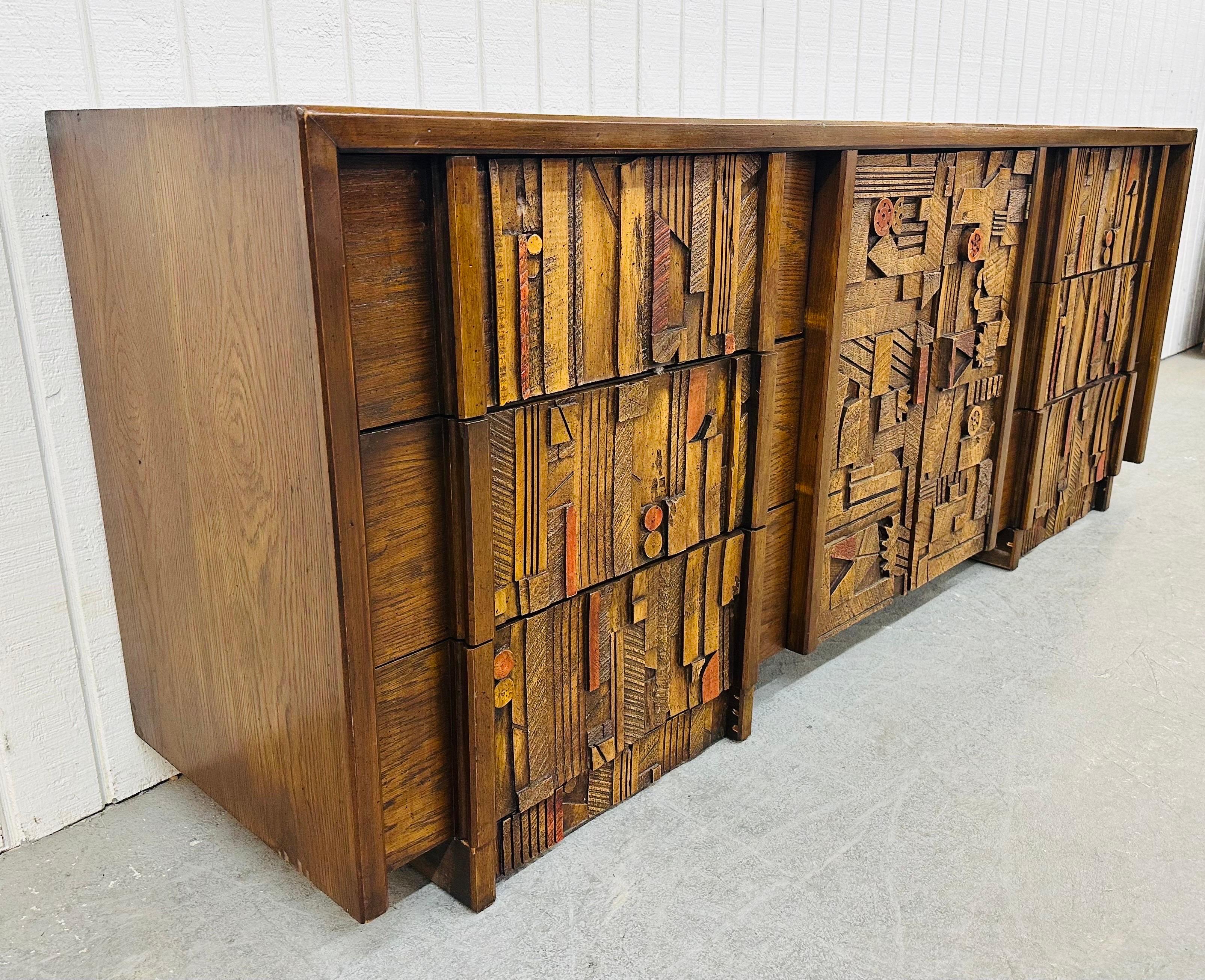 This listing is for a Mid-Century Modern Lane Pueblo Brutalist 9-Drawer Dresser. Featuring a straight line design, three large drawers on each side, center doors that open up to three hidden drawers, a brutalist geometrical Pueblo design across the