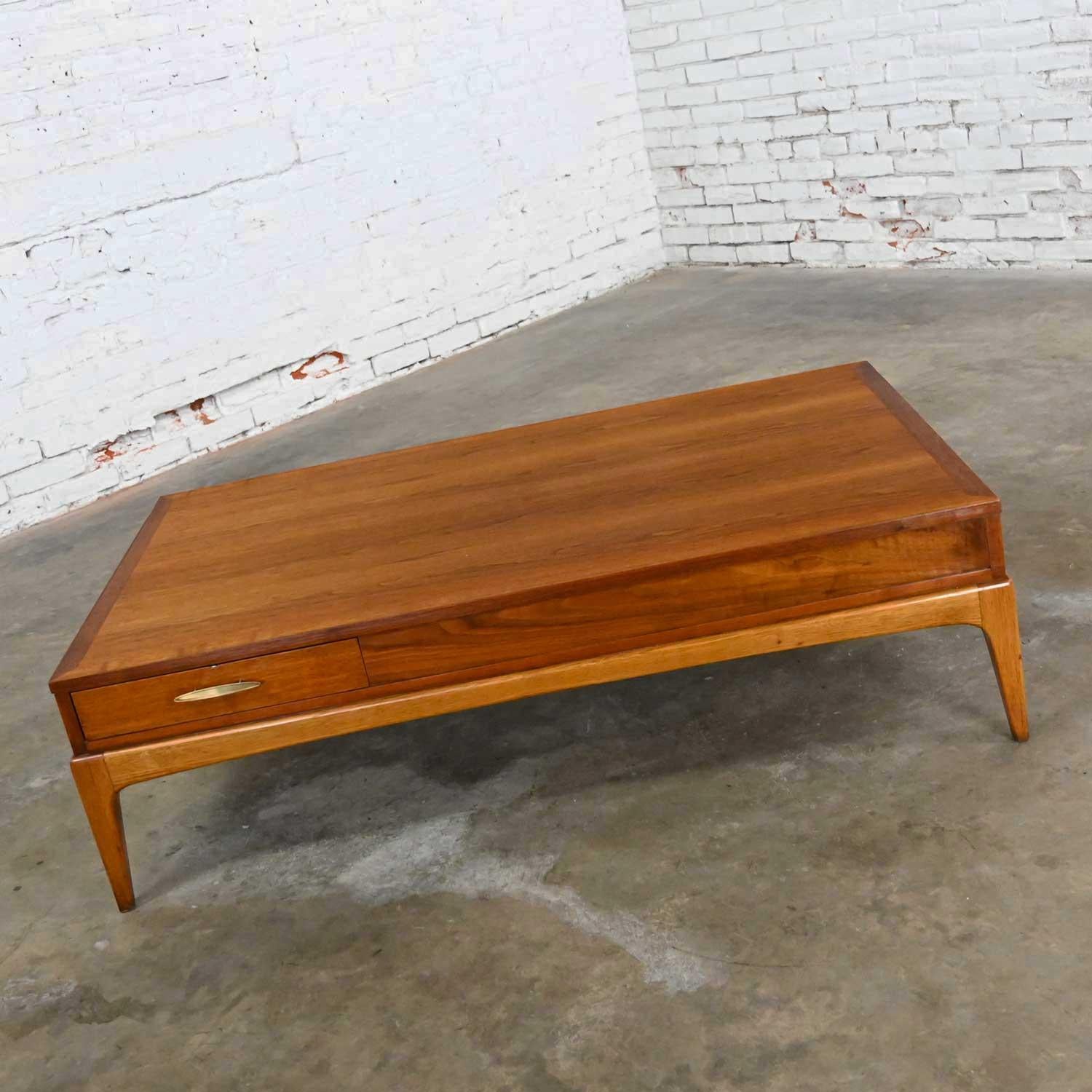 Iconic mid-century modern walnut coffee table with brass plated metal hardware by Lane Furniture for their Rhythm Collection. Beautiful condition, it has been completely restored. But keep in mind that this is vintage and not new so will have signs