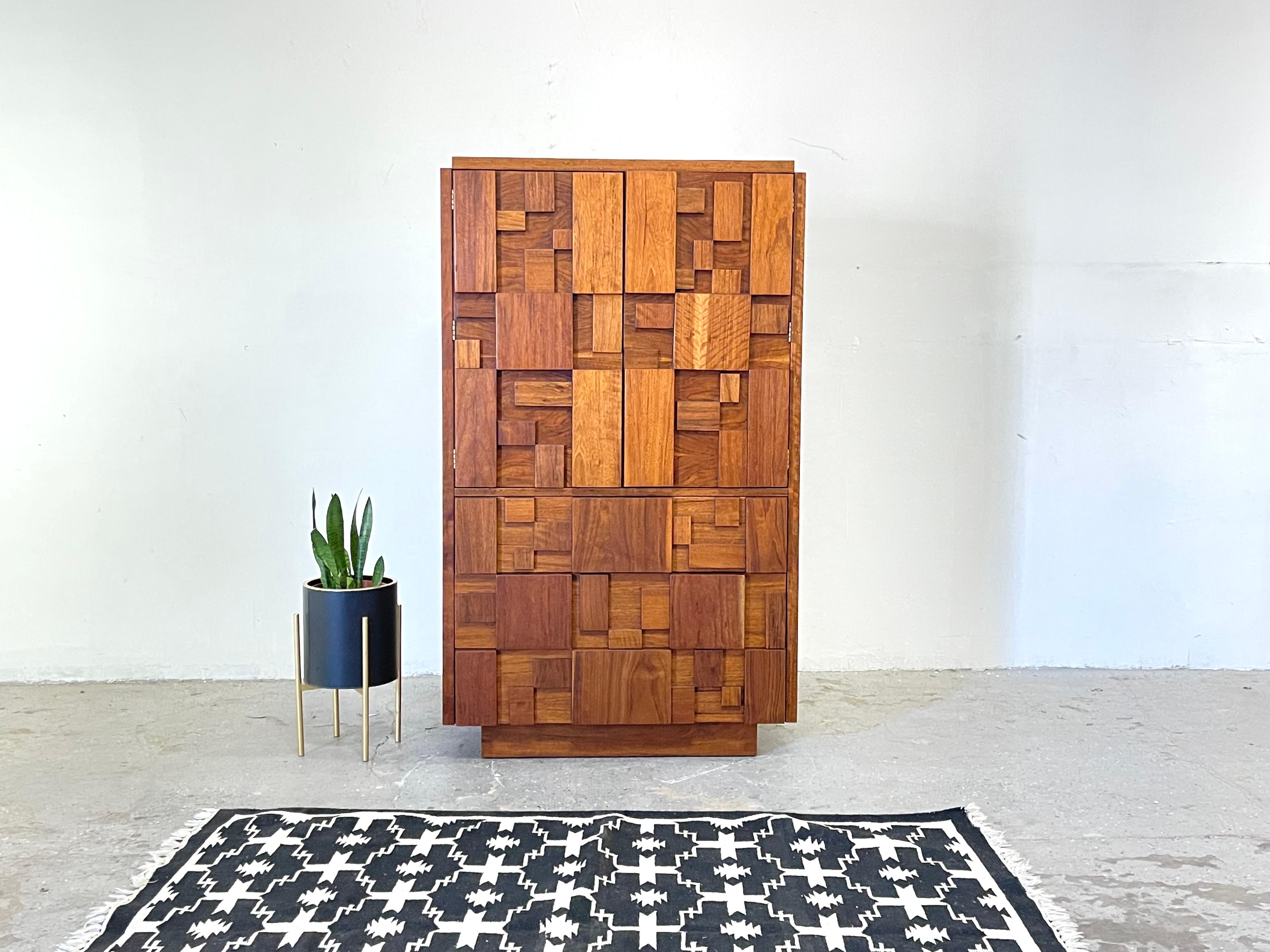 Vintage Mid-Century Modern brutalist armoire dresser from the “Staccato” line by Lane Furniture Company. Raised block front Brutalist style and period. The dresser, armoire, has two doors which open to reveal a lower drawer and open shelved storage.