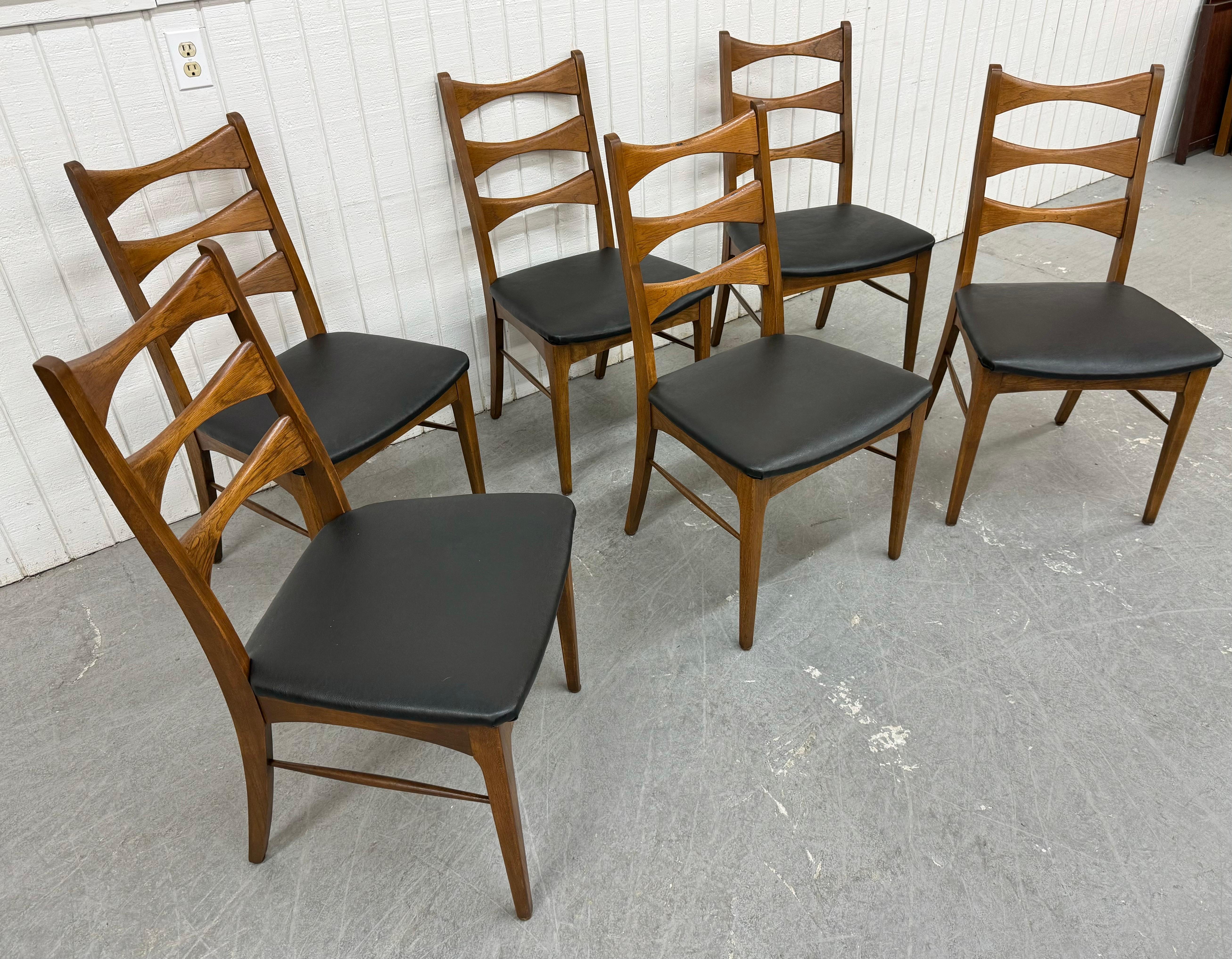 This listing is for a set of six Mid-Century Modern Lane Style Dining Chairs. Featuring a ladder back design, solid wood construction, newly upholstered black vinyl seats, and a beautiful walnut finish. This is an exceptional combination of quality