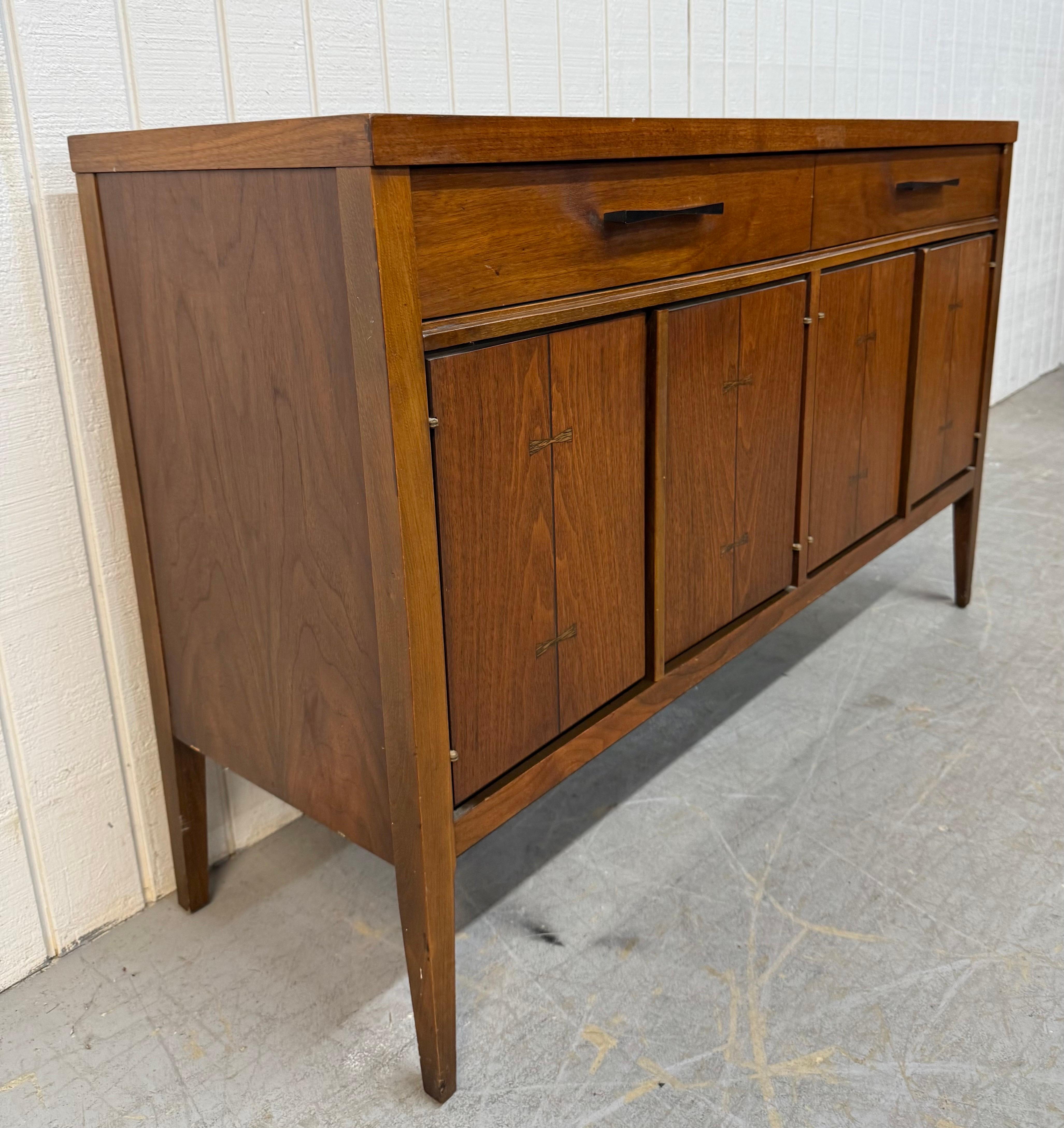 Dieses Angebot bezieht sich auf einen Mid-Century Modern Lane's Tuxedo Walnut Server. Mit einem geradlinigen Design, zwei Schubladen mit originalen schwarzen Metallbeschlägen, Türen auf jeder Seite, die sich öffnen lassen, um Stauraum zu schaffen,