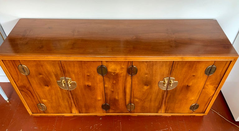 A Chinoiserie style midcentury credenza by Lane Furniture, Altavista, VA. Made of walnut with brass hardware throughout. Pair of front doors open to drawers and shelving. Multipurpose, would make a great server, buffet, entertainment console or dry