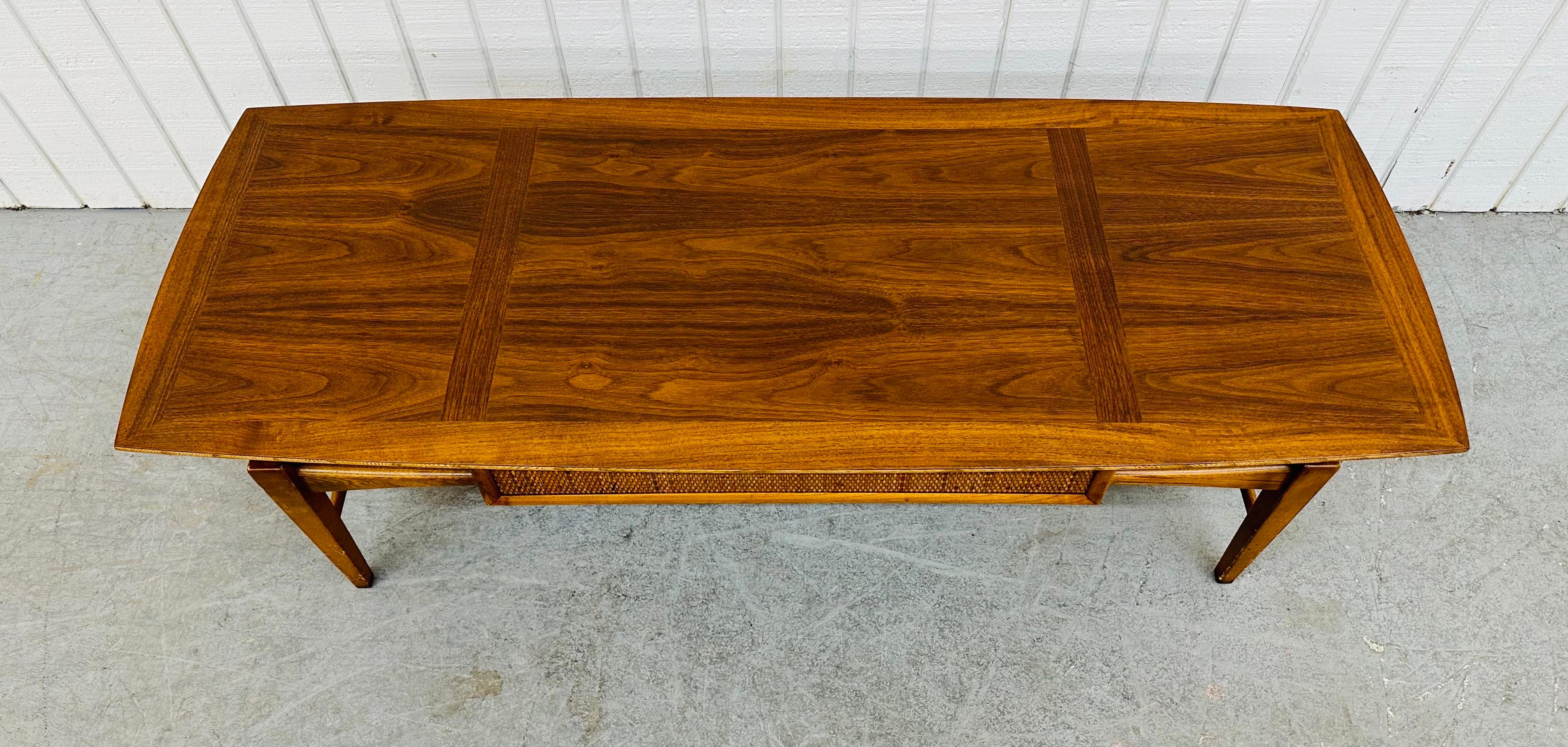 This listing is for a Mid-Century Modern Lane Walnut Coffee Table. Featuring a straight line design, freeform wooden base, cane front drawer, and a beautiful walnut finish. This is an exceptional combination of quality and design by Lane!