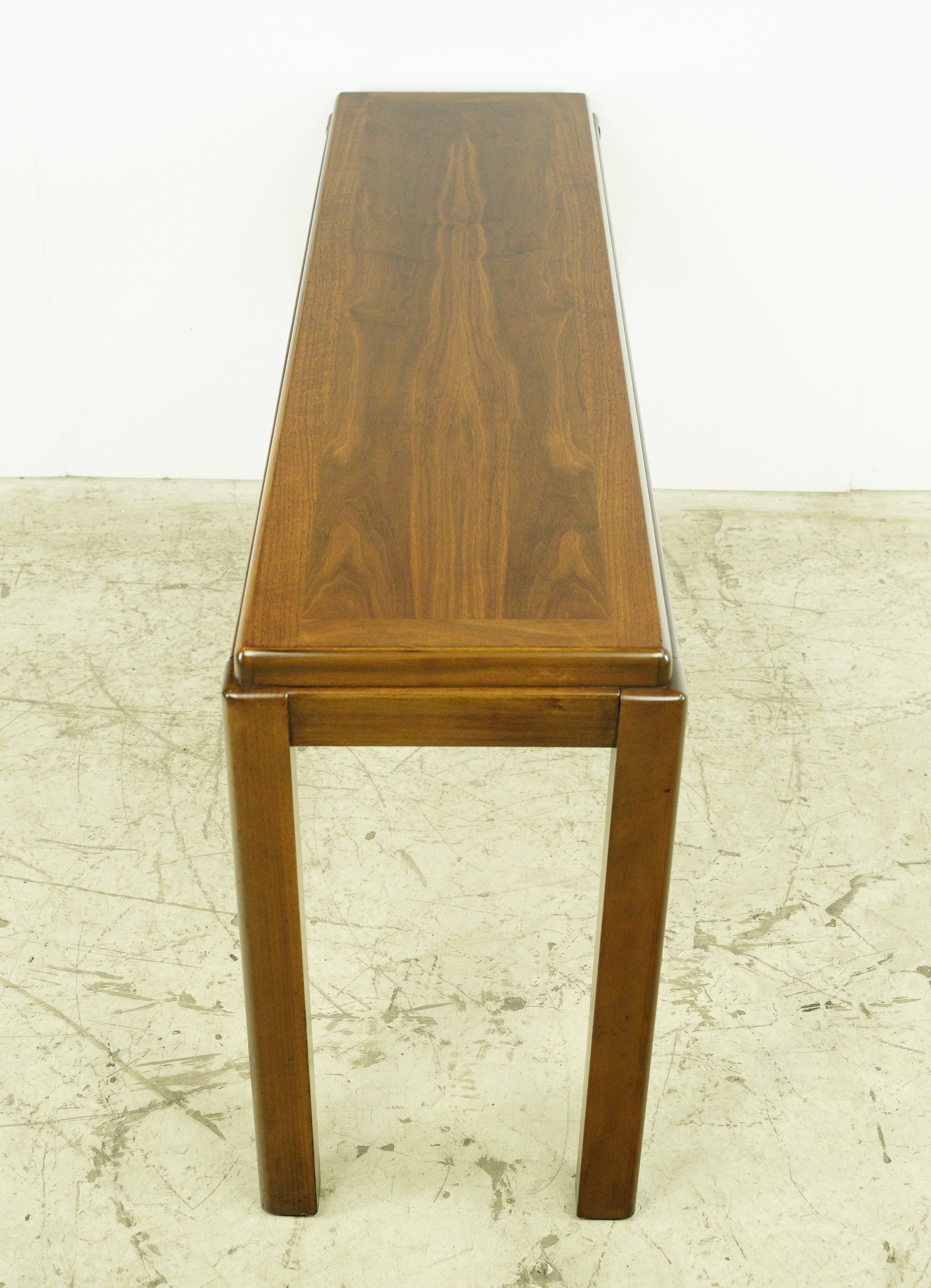 Mid-Century Modern style walnut rectangular shaped console table with a dark stain. The table features a classic style, with a flat top surface and four straight legs. Made by Lane Furniture Company. This type of table is designed to be placed
