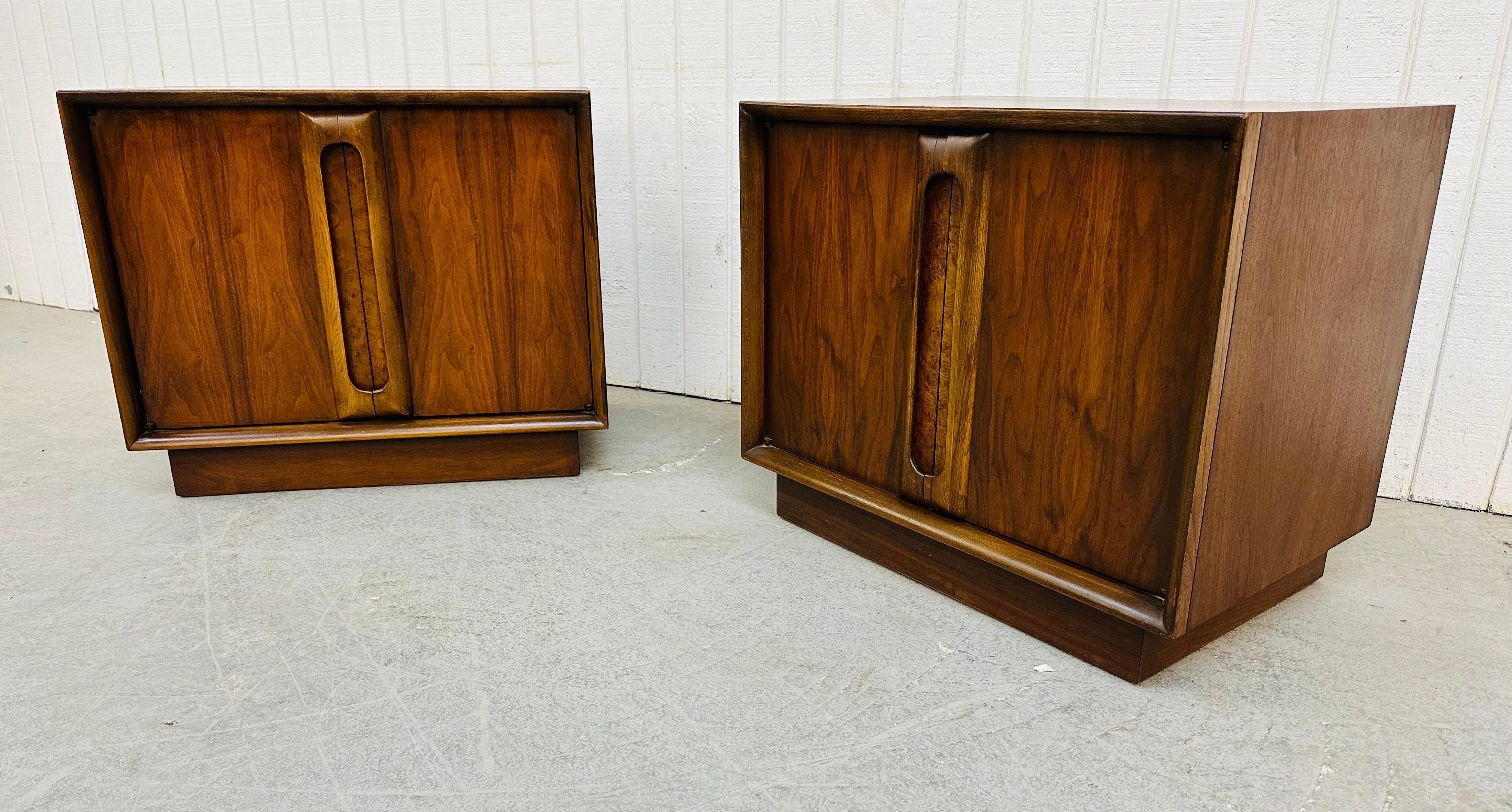 This listing is for a pair of Mid-Century Modern Lane Walnut Cube Nightstands. Featuring a straight line design, cube shaped on a plinth base, two doors with wood handles that open up to storage space, burled accent at the edge of each door, and a