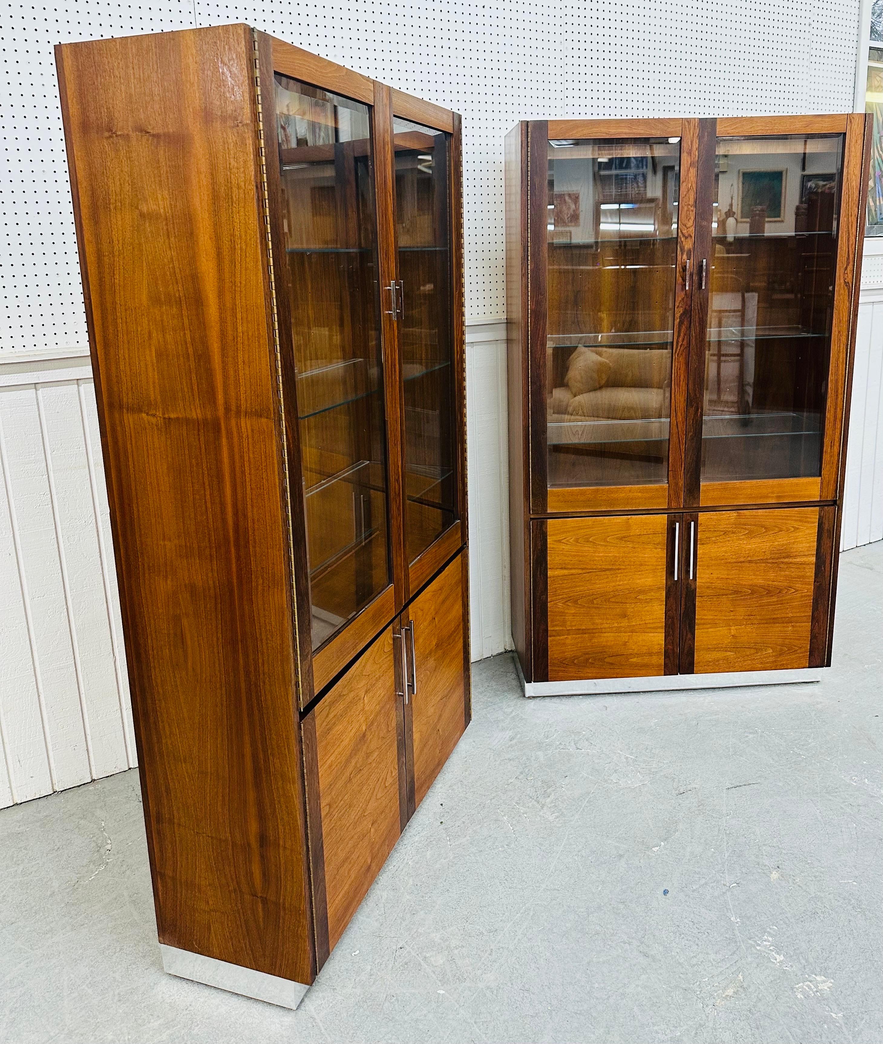 This listing is for a pair of Mid-Century Modern Lane Walnut Display Cabinets. Featuring a straight line design, two glass doors that open up to three glass shelves for storage, two cabinet doors at the bottom that open up to shelving for more