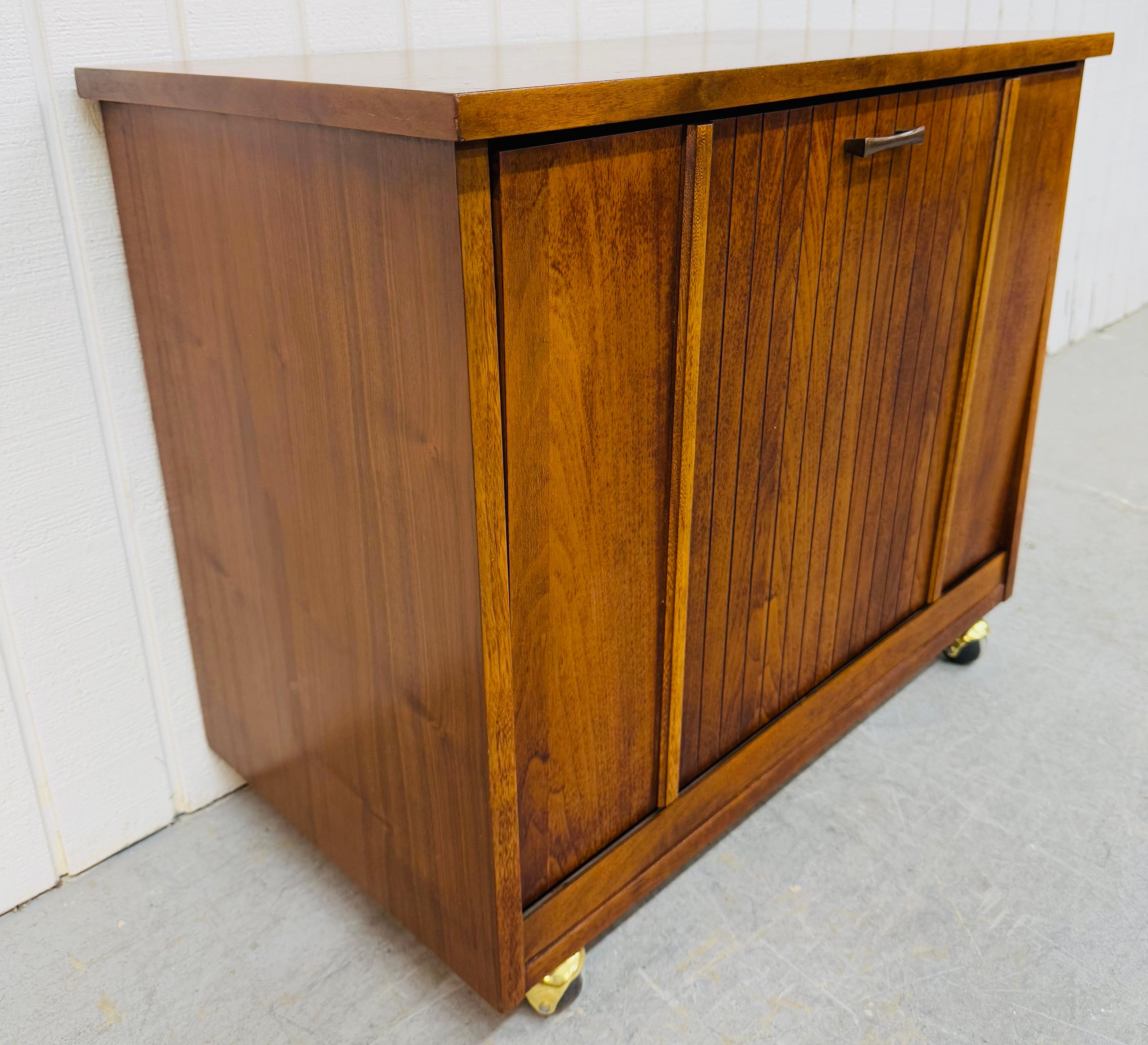 This listing is for a Mid-Century Modern Lane Walnut Record Cabinet. Featuring a straight line design, drop front door that opens up to divided record storage space, wheels for easy movement, and a beautiful walnut finish. This is an exceptional