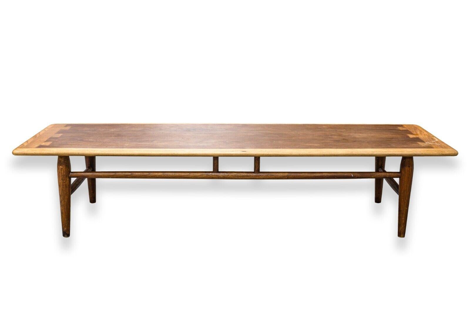 A mid century modern Lane walnut wood low rectangular coffee table. An elegant coffee table from US furniture manufacturer, Lane Furniture. This piece features a gorgeous walnut wood construction, with a unique crafted wood design. The four legs are