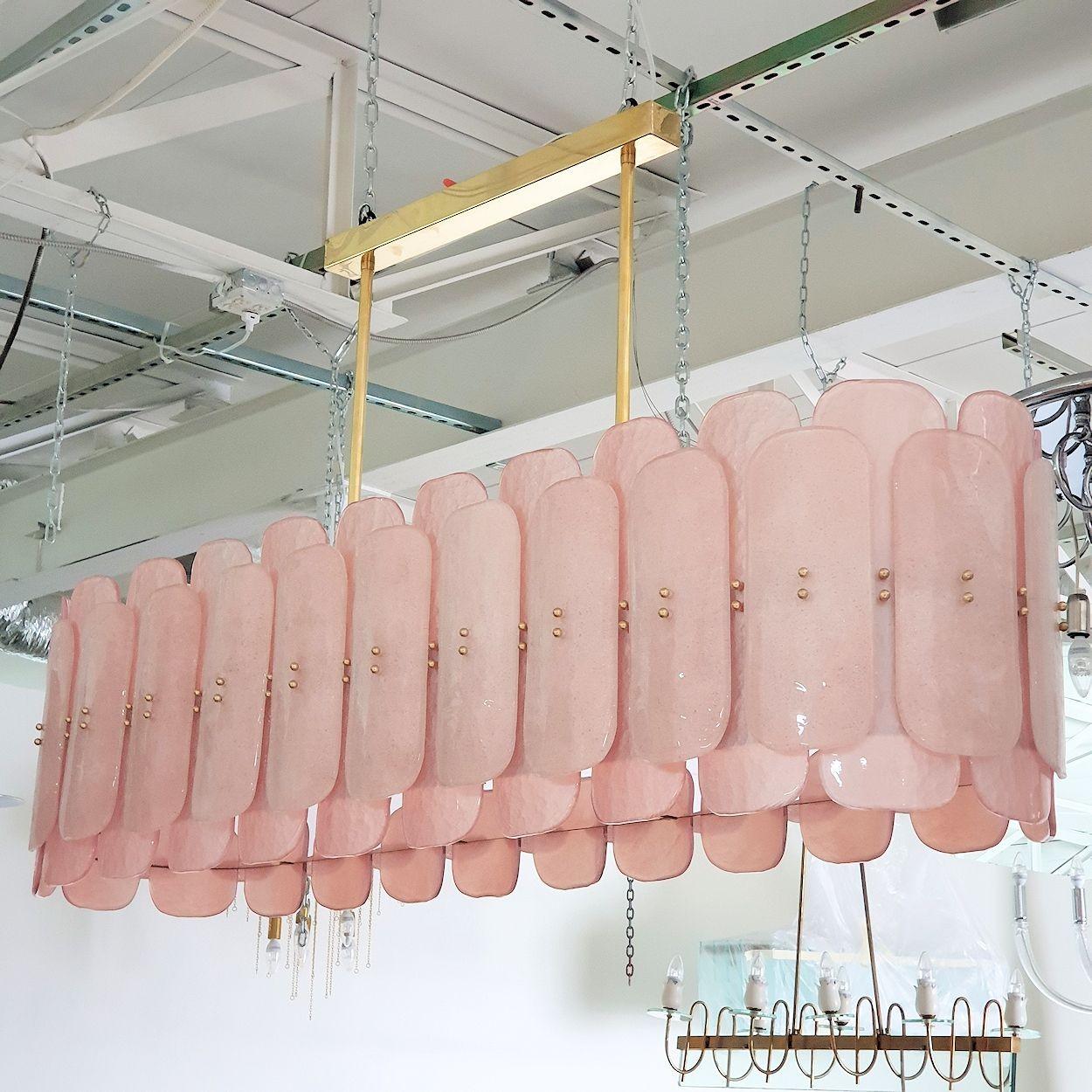 Very large elongated Murano glass chandelier, Mid Century Modern, Italy circa 1980s.
The Mid Century Modern chandelier is made of pastel pink translucent Murano glass and brass mounts.
The transitional style chandelier has 16 lights, 8 up, 8 down.