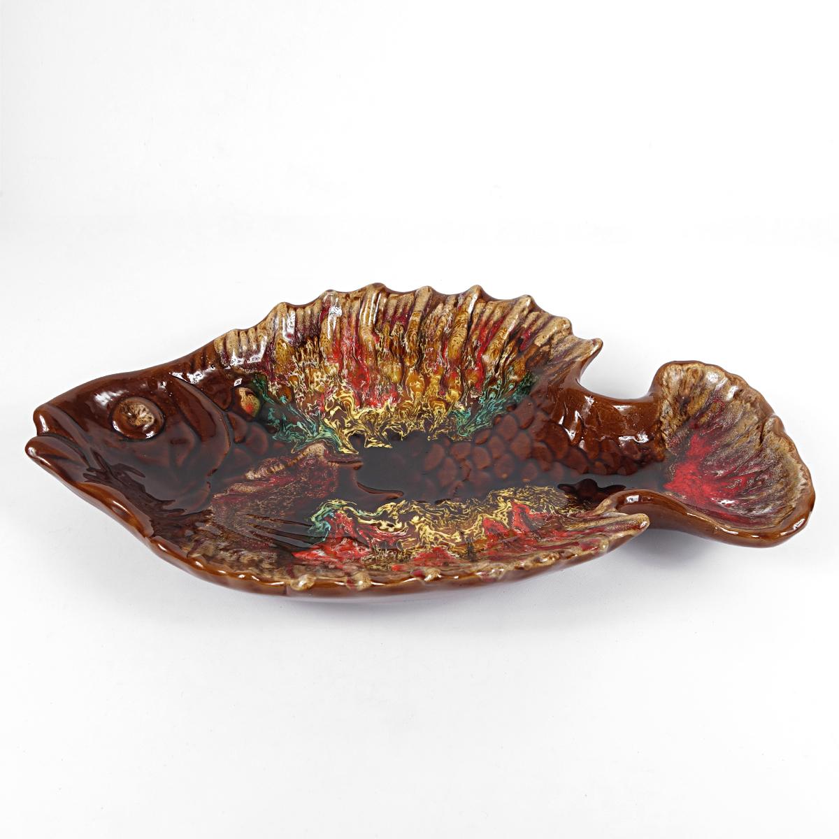 This is a very festive piece, probably dating from the 1950s, made by French manufacturer Vallauris:
a large and rather high plate or bowl in the shape of a fish. The perfect way of presenting your self cooked seabass or gilthead.
The beautiful