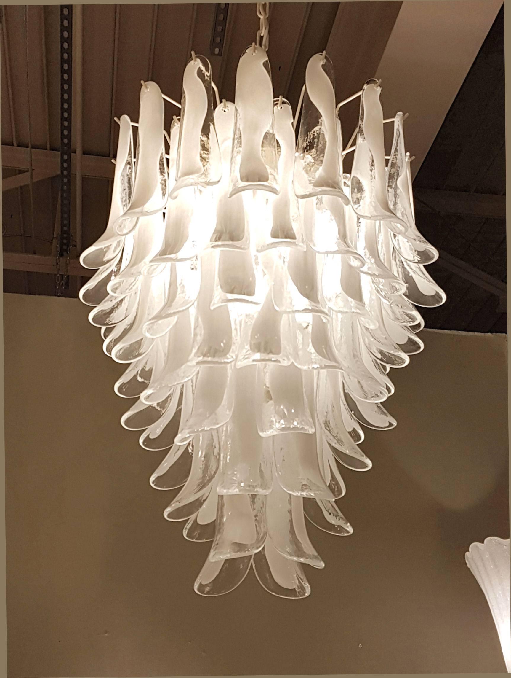Mid-Century Modern white and clear Murano glass petals chandelier.
By Mazzega, Italy, 1970s.
Eight-tiers Murano chandelier. Seven candelabra base lights, rewired. 
Ivory metal frame and chain. 
The white and clear petals keep their white color