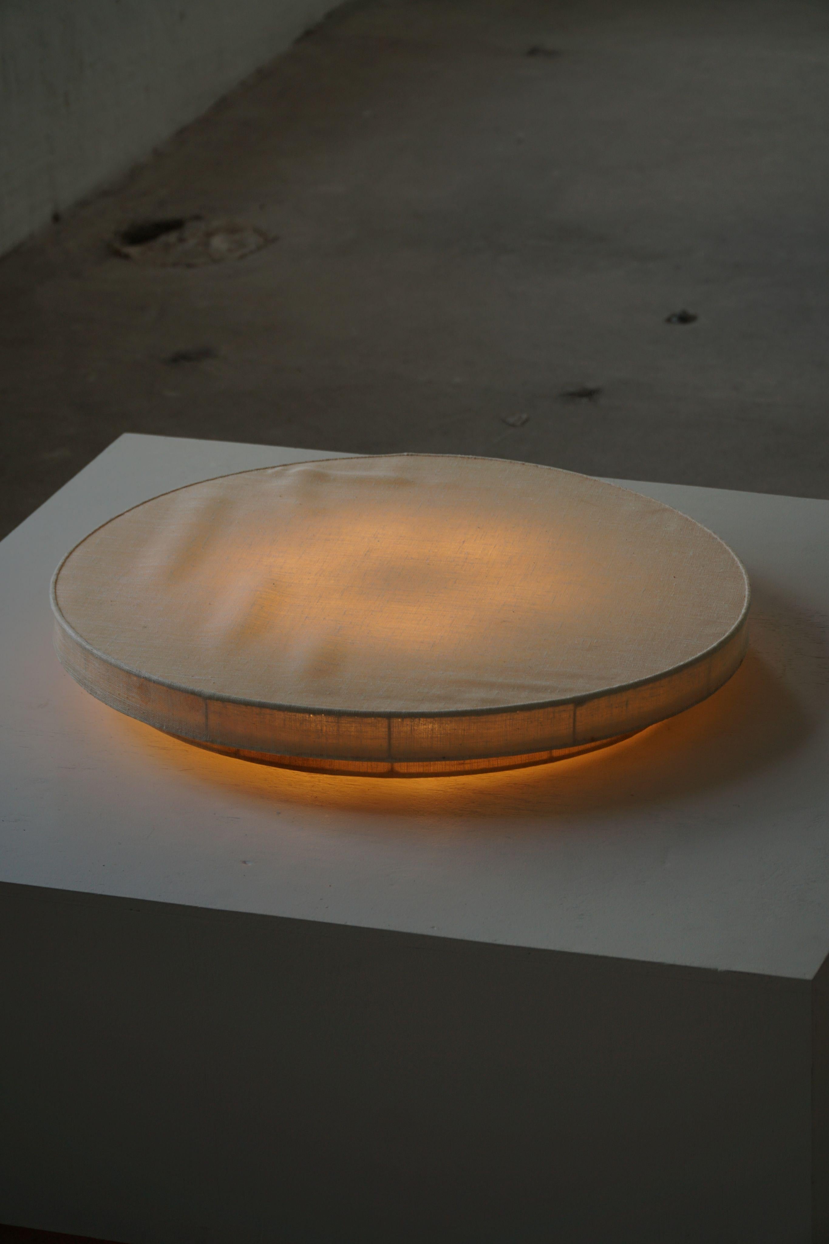 Elegant plafonnier rond/affleurant du milieu du siècle dernier, datant des années 1950-1960. Doté d'un généreux abat-jour en lin de 76 cm de diamètre, ce luminaire adoucit et diffuse magnifiquement la lumière, créant ainsi un éclairage ambiant
