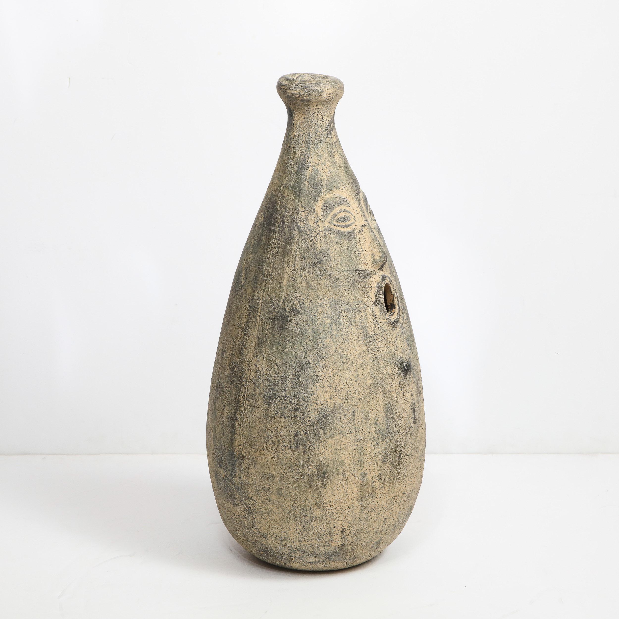 This sophisticated Mid-Century Modern large scale figurative vase was realized in the United States, circa 1960. Created in ceramic, the piece offers a stylized human face with its distinguishing feature reduced to abstracted forms, in the manner of