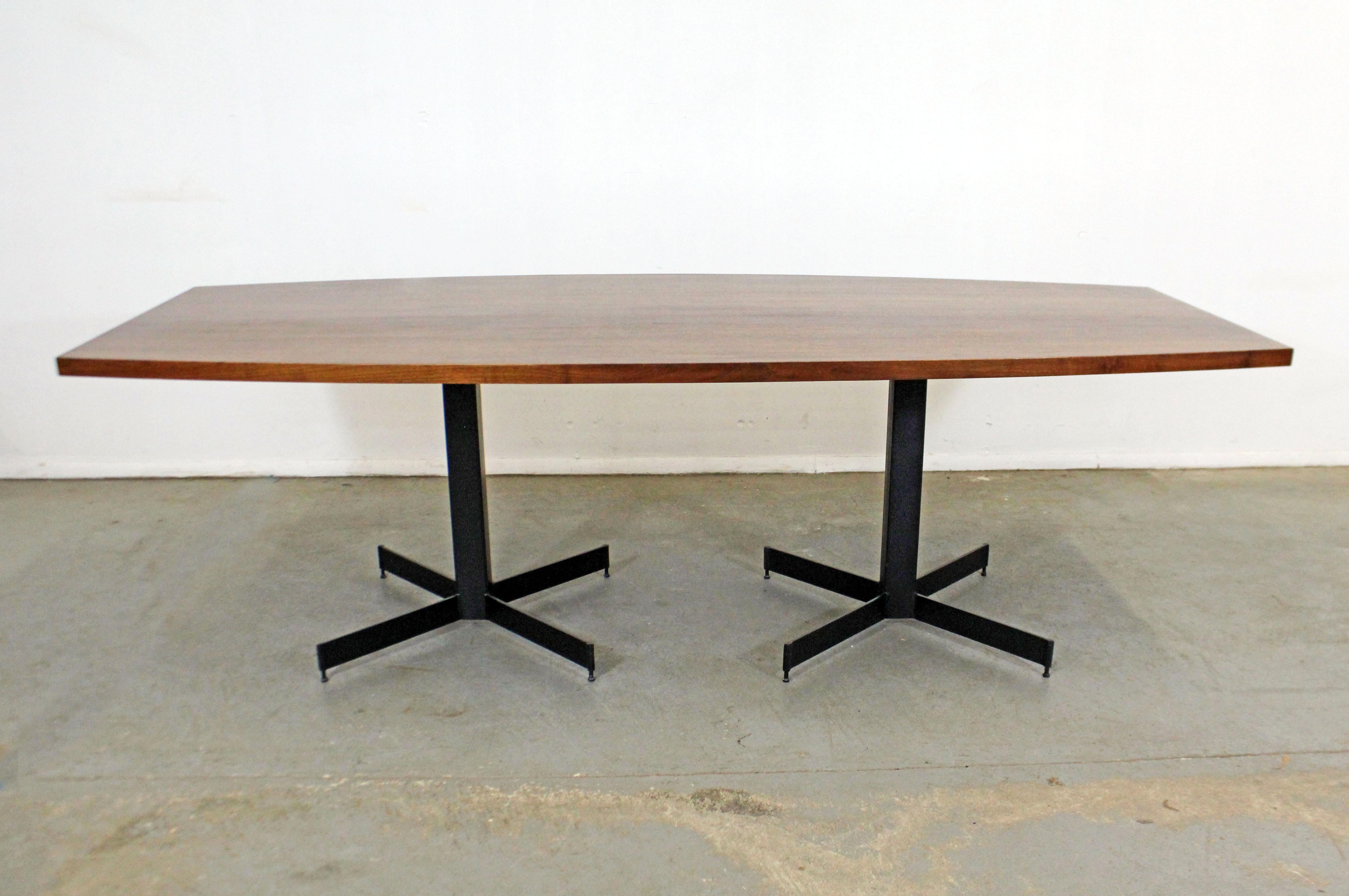 Offered is a large Mid-Century Modern conference/dining table. This table has been recently restored with a refinished walnut 
surfboard-shaped top and two black pedestal bases. In good condition for its age with some surface scratches throughout.