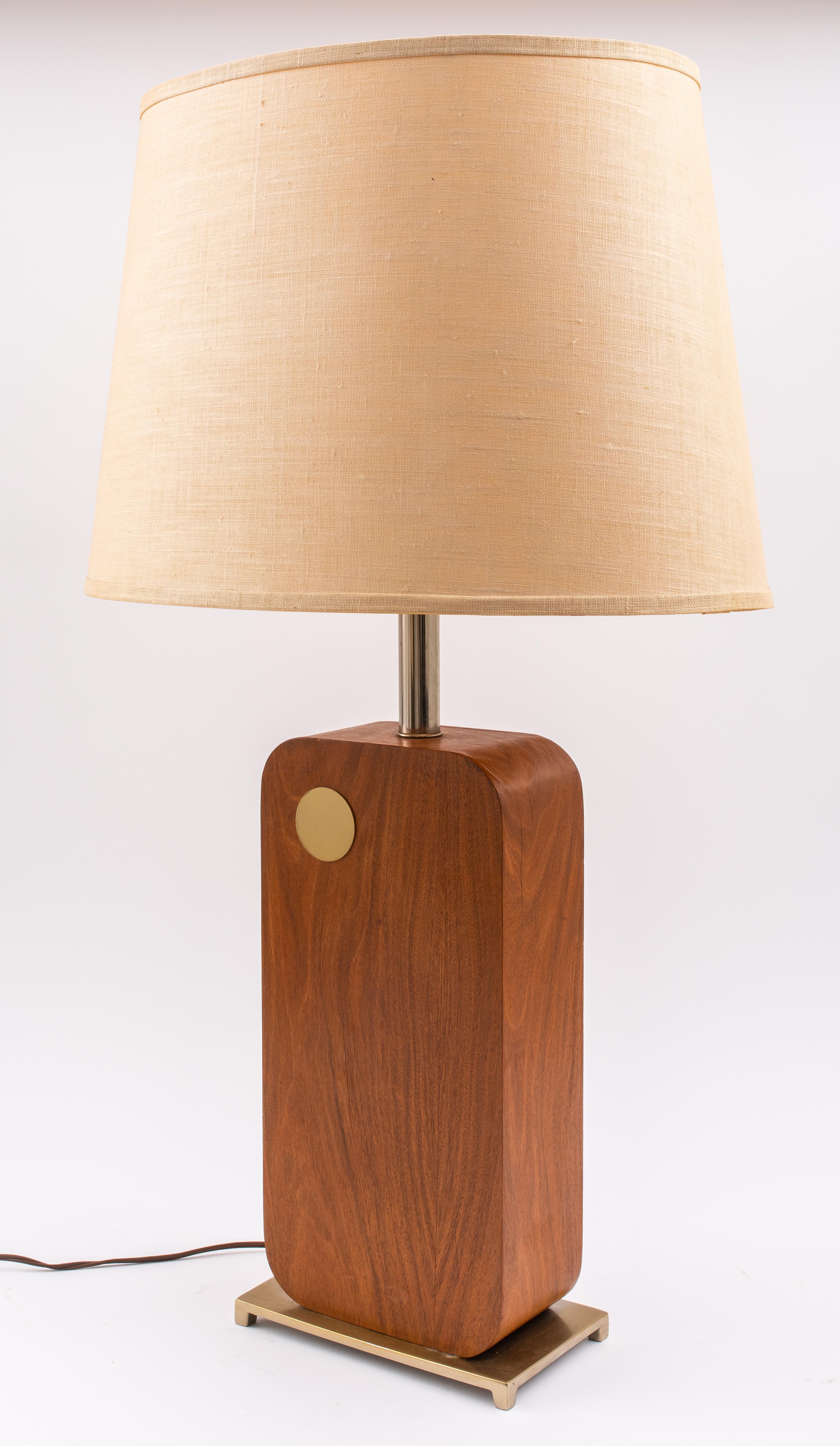 Mid-Century Modern table lamp by Laurel Lighting Company, the rectangular gilt brass base mounted by a wood rectangle with rounded edges and a gold-tone metal circle accent, with a beige linen shade, marked 