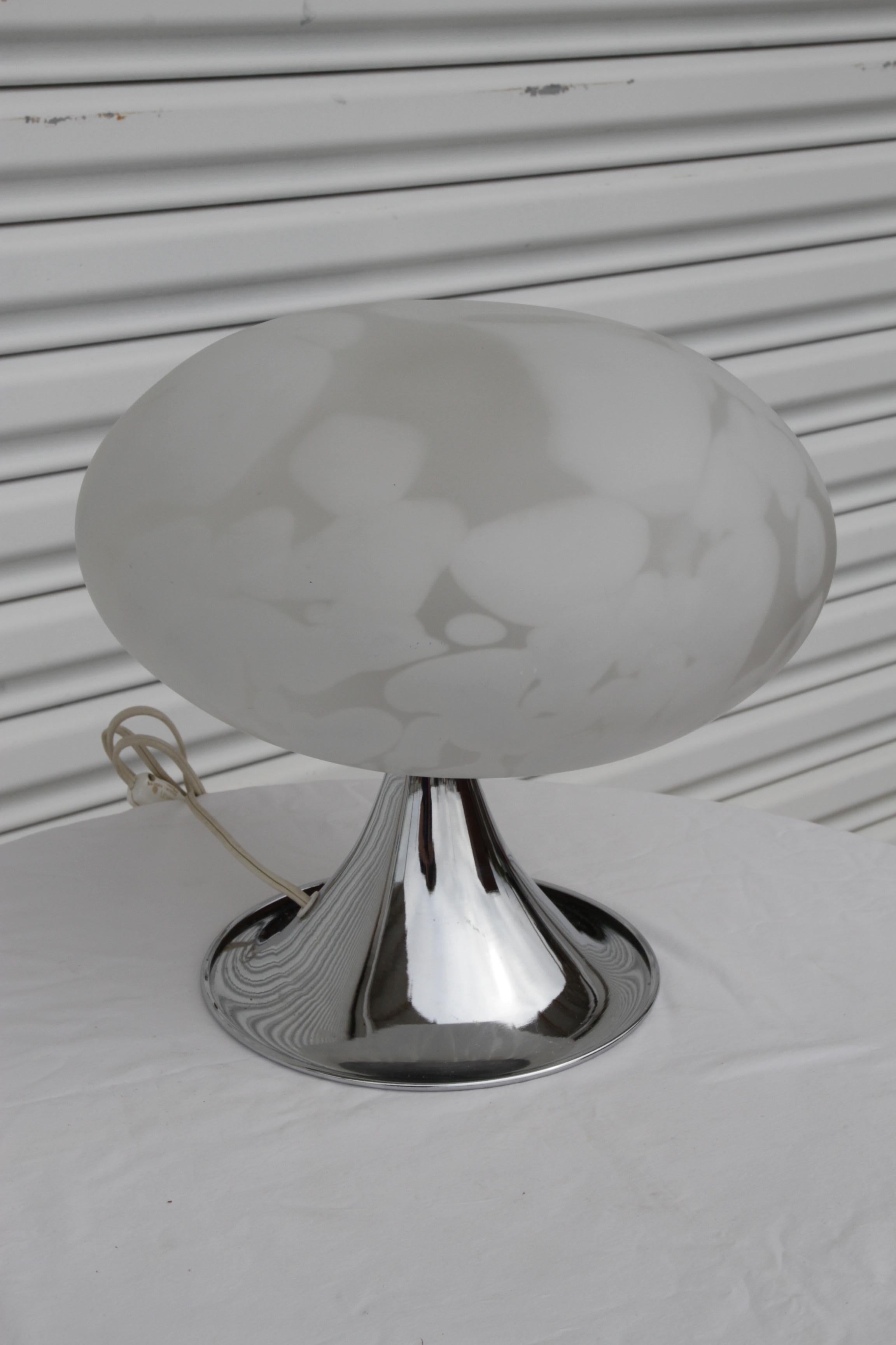 Questa moderna lampada da tavolo a fungo è caratterizzata da un'imponente base cromata e da un elegante paralume in vetro di Murano con un esclusivo motivo a vortice bianco, che crea una luce morbida e diffusa. Il design moderno di metà secolo della