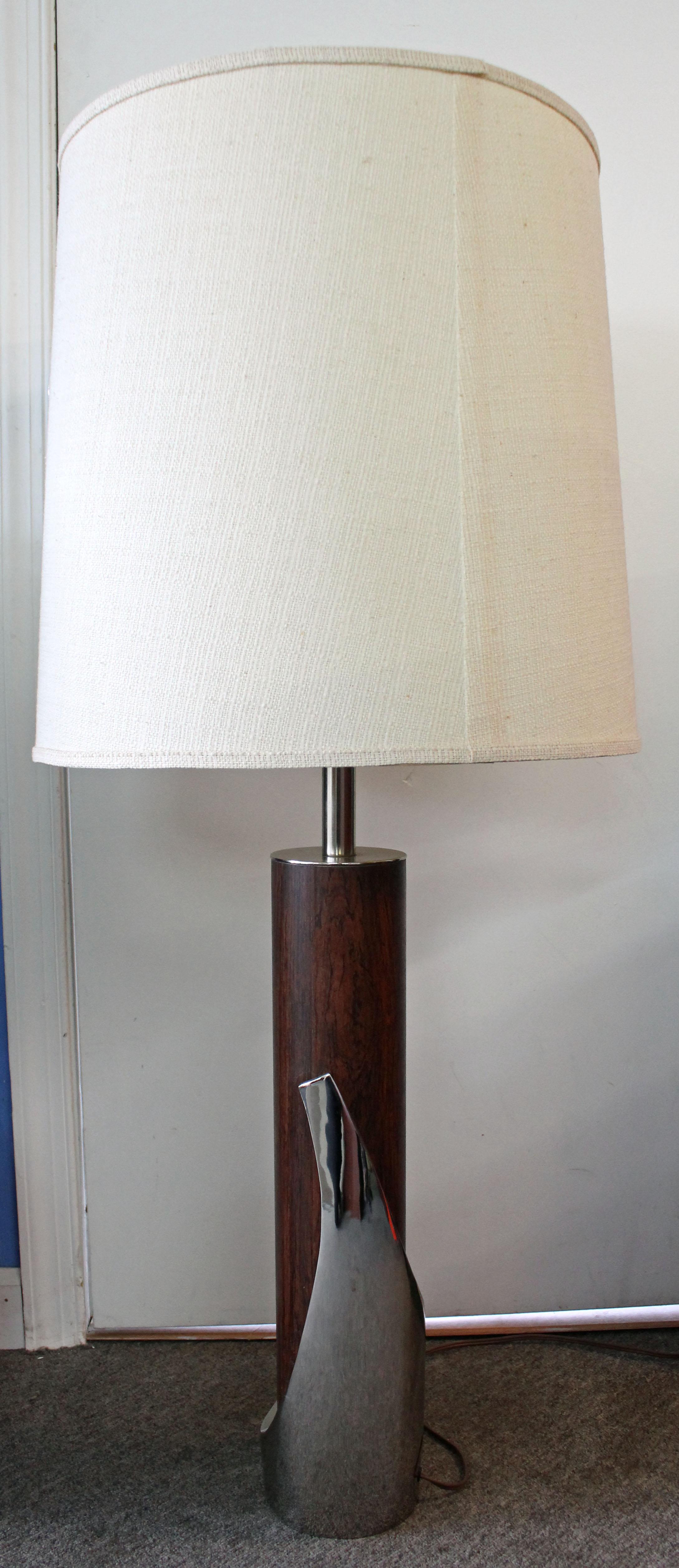 Offered is a Mid-Century Modern lamp made by Laurel Lamp Co. This piece is super cool, made of faux walnut and cast aluminium sculptural detail. It is in great, working condition given its age. The shade is not included, for display purposes only.