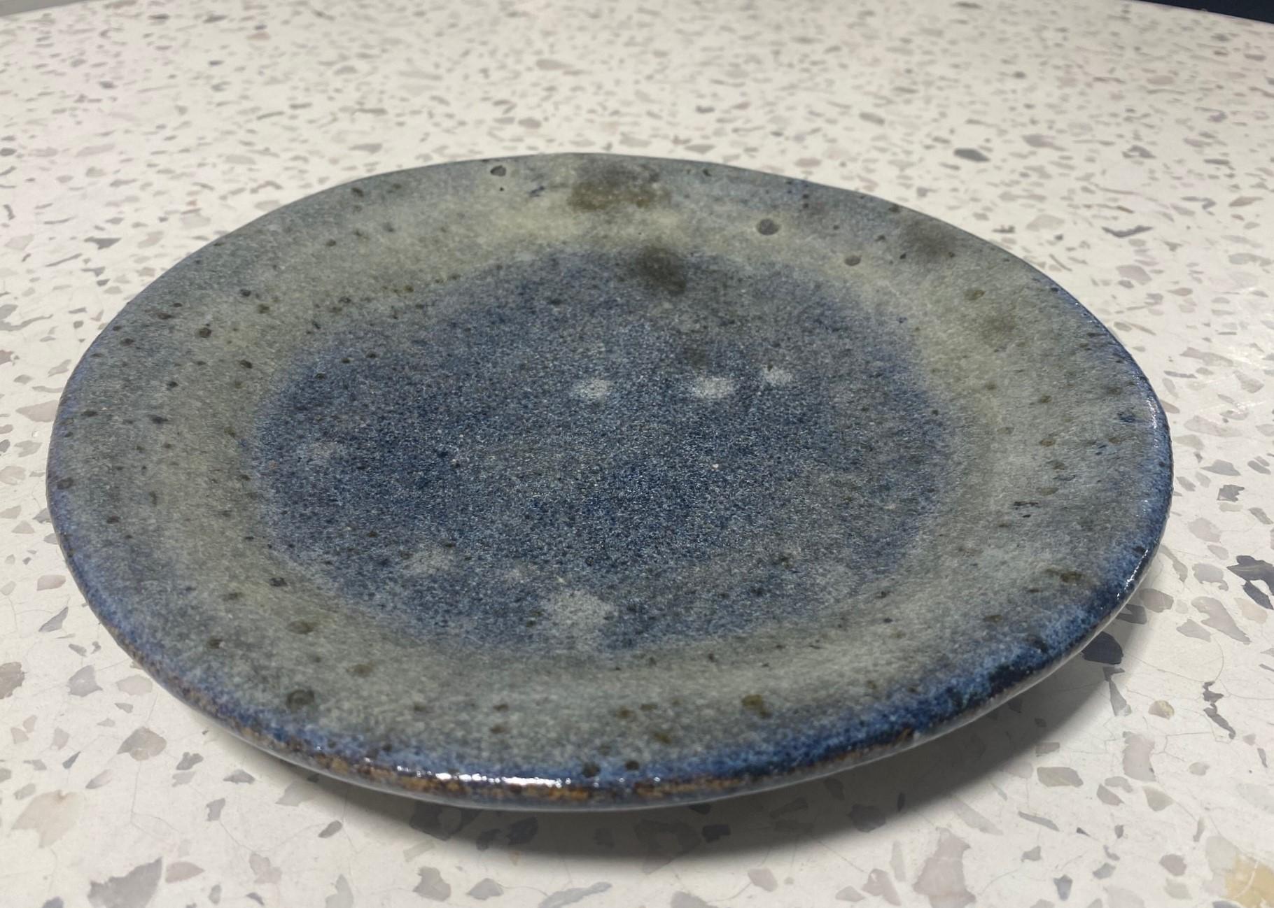 A wonderfully designed and blue lava crater glazed studio pottery plate in the style of Mid-Century California master potters Beatrice Wood, Glen Lukens, and Otto and Gertrud Natzler.  The sumptuous glaze is quite something - especially on the verso